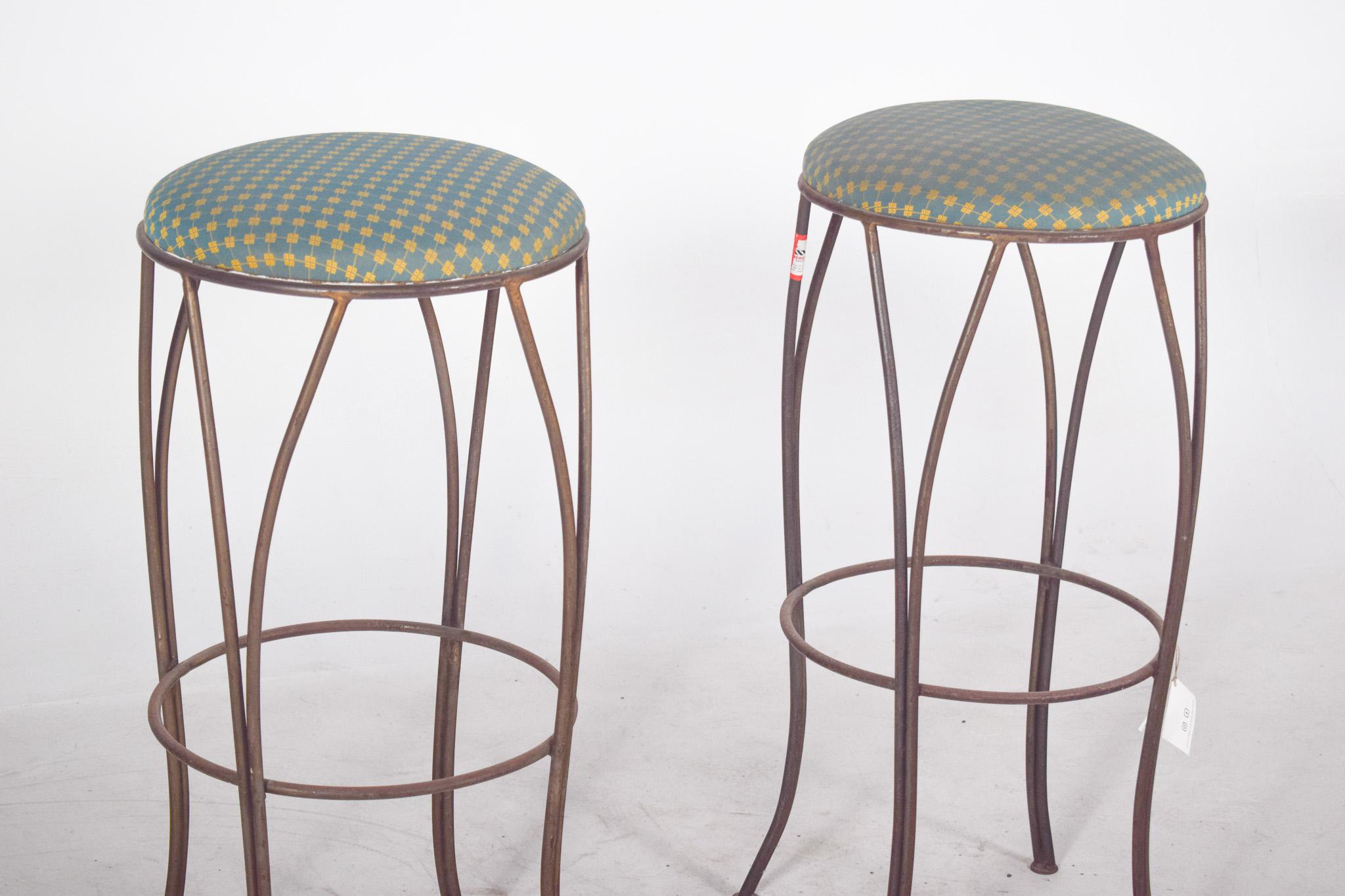 Coppia di sgabelli alti in metallo. Ideali per bar, cucine o banconi, hanno un design elegante e sottile. Con quattro gambe ricurve in metallo ossidato, dimostrano stabilità e un discreto tocco industriale. I poggiapiedi circolari collegano le gambe