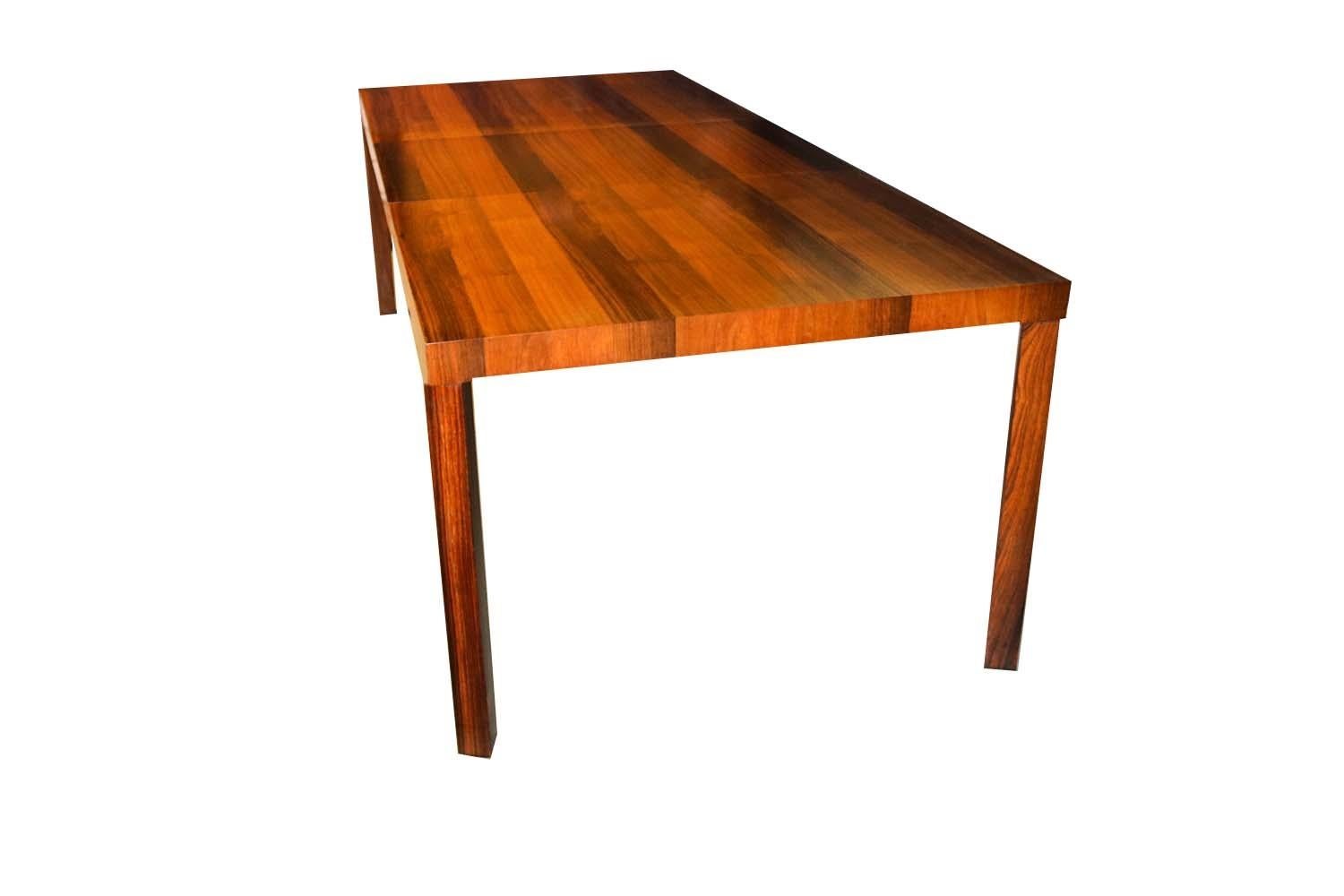 A spectacular tri-wood midcentury Parsons dining table by Dyrlund of Denmark, circa 1960. This beautiful vintage Parsons table by Dyrlund features alternating veneers of rosewood, teak and walnut over four solid rosewood legs and includes one leaf.