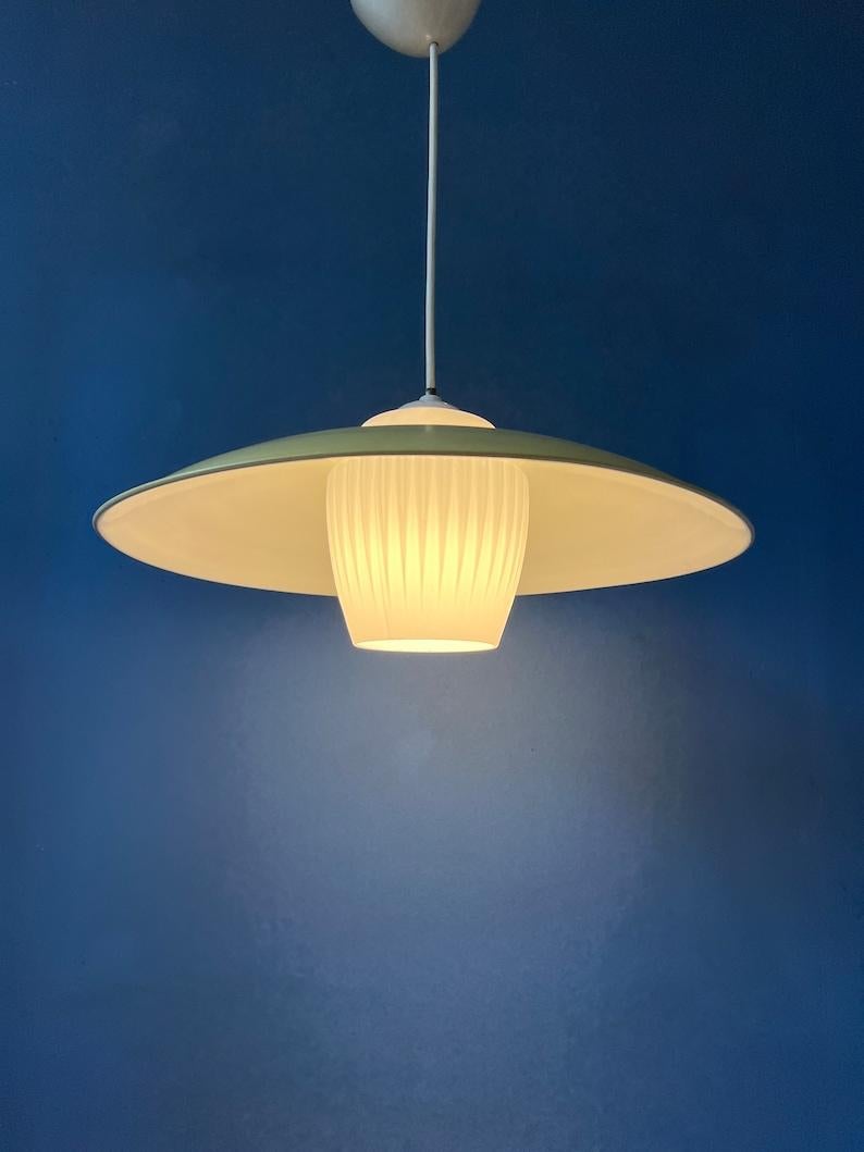 Delicate mid century pendant lamp with opaline glass inner shade and yellow metal outer shade. The glass shade is perfectly shaped so it fits right in the metal cover. The lamp requires one E27/26 (standard) lightbulb.

Additional