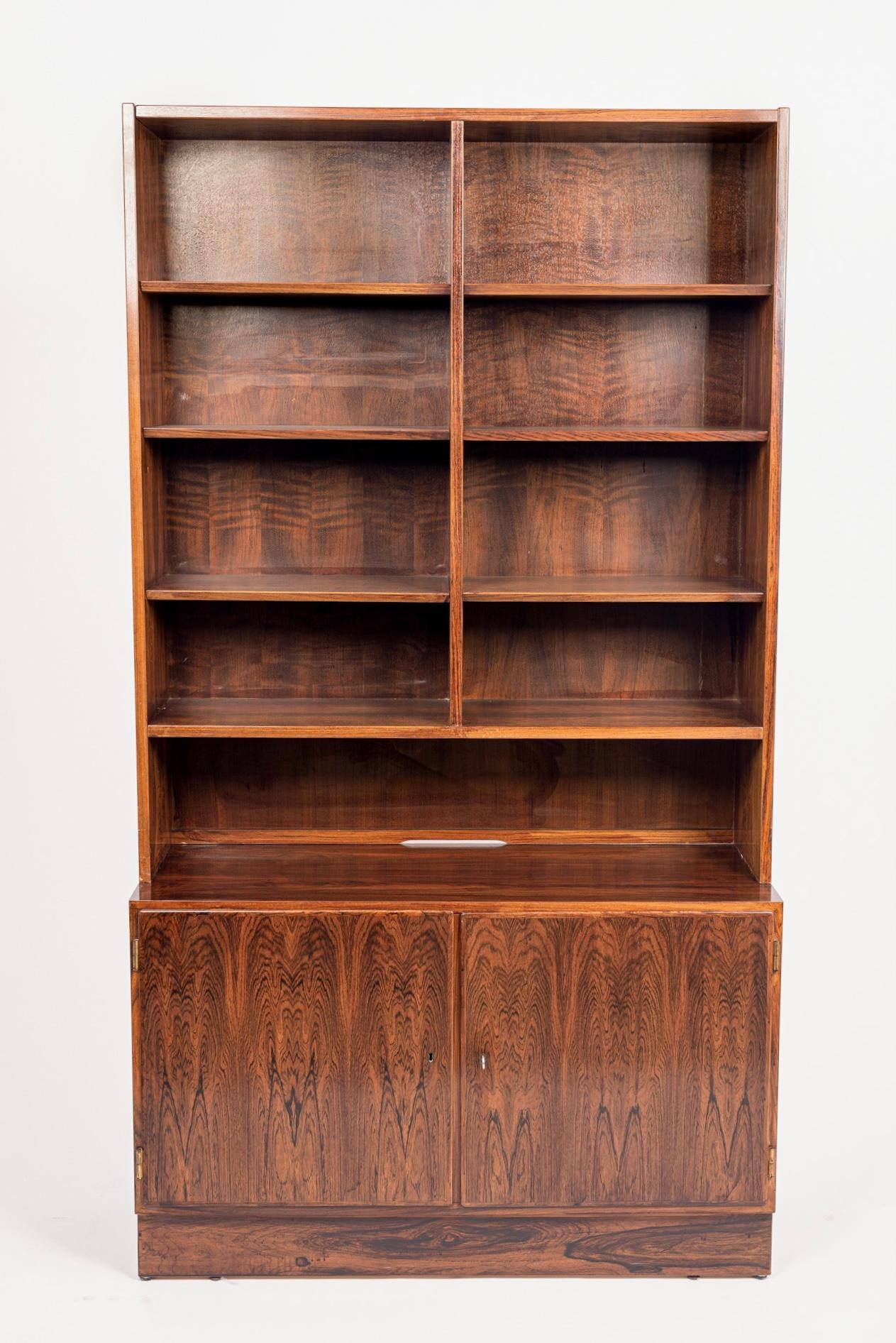 This vintage midcentury Danish modern two-piece rosewood bookcase designed by Carlo Jensen for Hundevad & Co. was made in Denmark circa 1960. The Minimalist Scandinavian Modern design features clean, geometric lines and the cabinet is impeccably