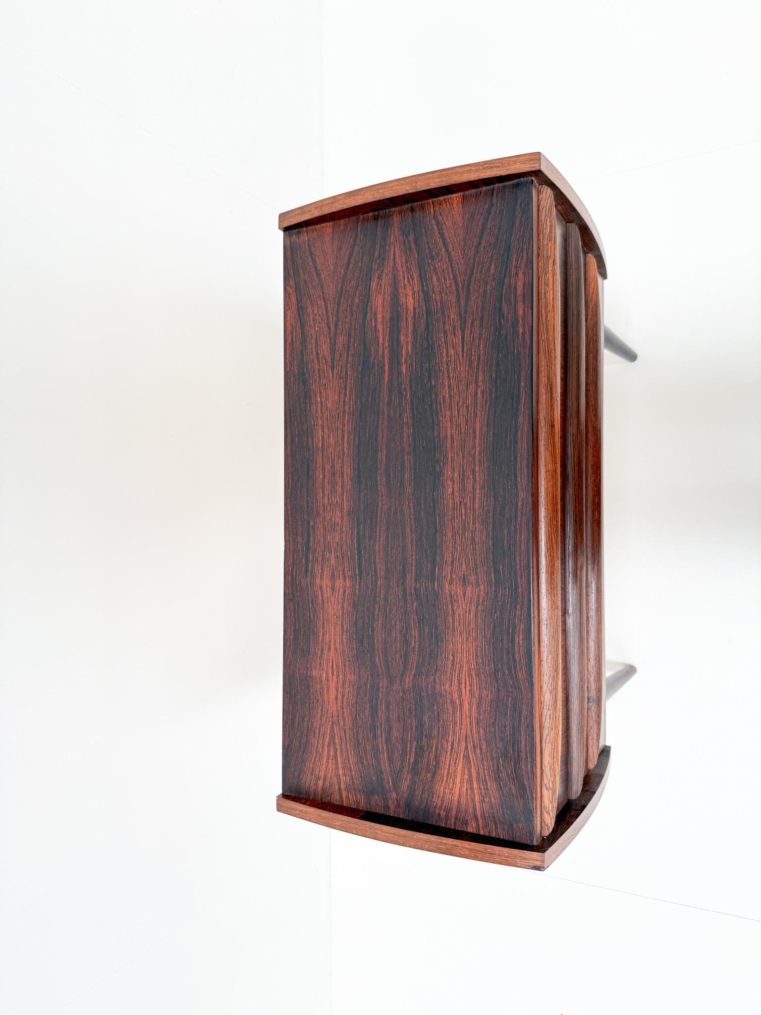 Elegant mid-century modern chest of drawers in rosewood, crafted in Denmark during the 1960s. This compact piece features three drawers with beautifully integrated handles and showcases the striking natural grain of the rosewood veneer. Raised on
