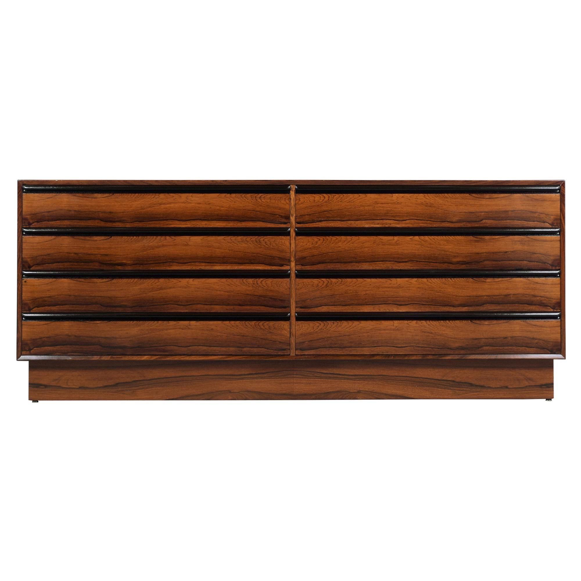 A remarkable Danish modern chest of drawers that has been professionally restored, is hand-crafted out of rosewood and has been newly finished in mahogany and ebonized color combination. The dresser features eight drawers each with carved handles
