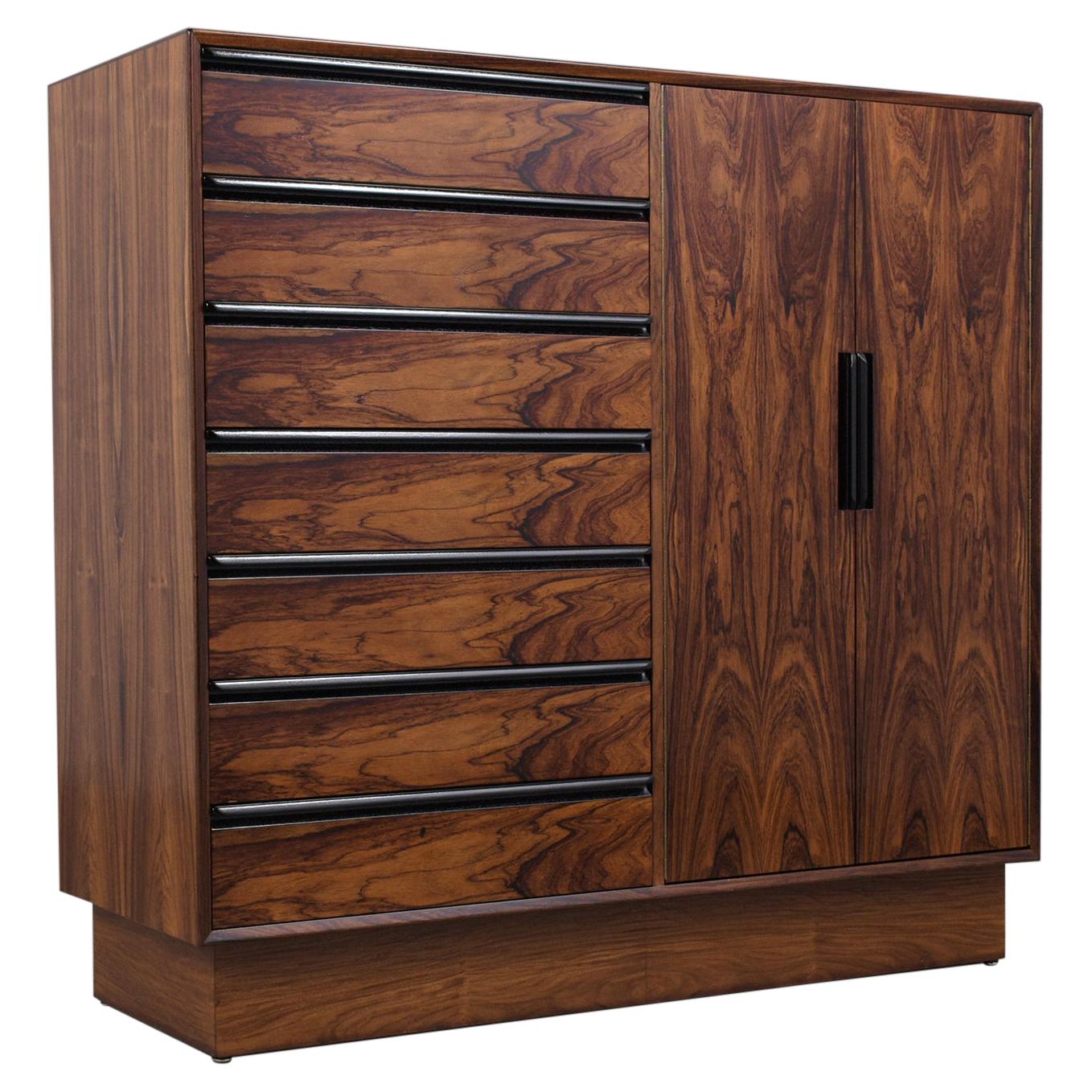 A remarkable Danish modern bachelor chest of drawers is hand-crafted out of rosewood, has been newly stained with a lacquered finish, and is fully restored by our team of craftsmen. The dresser comes with seven interior drawers behind double doors,