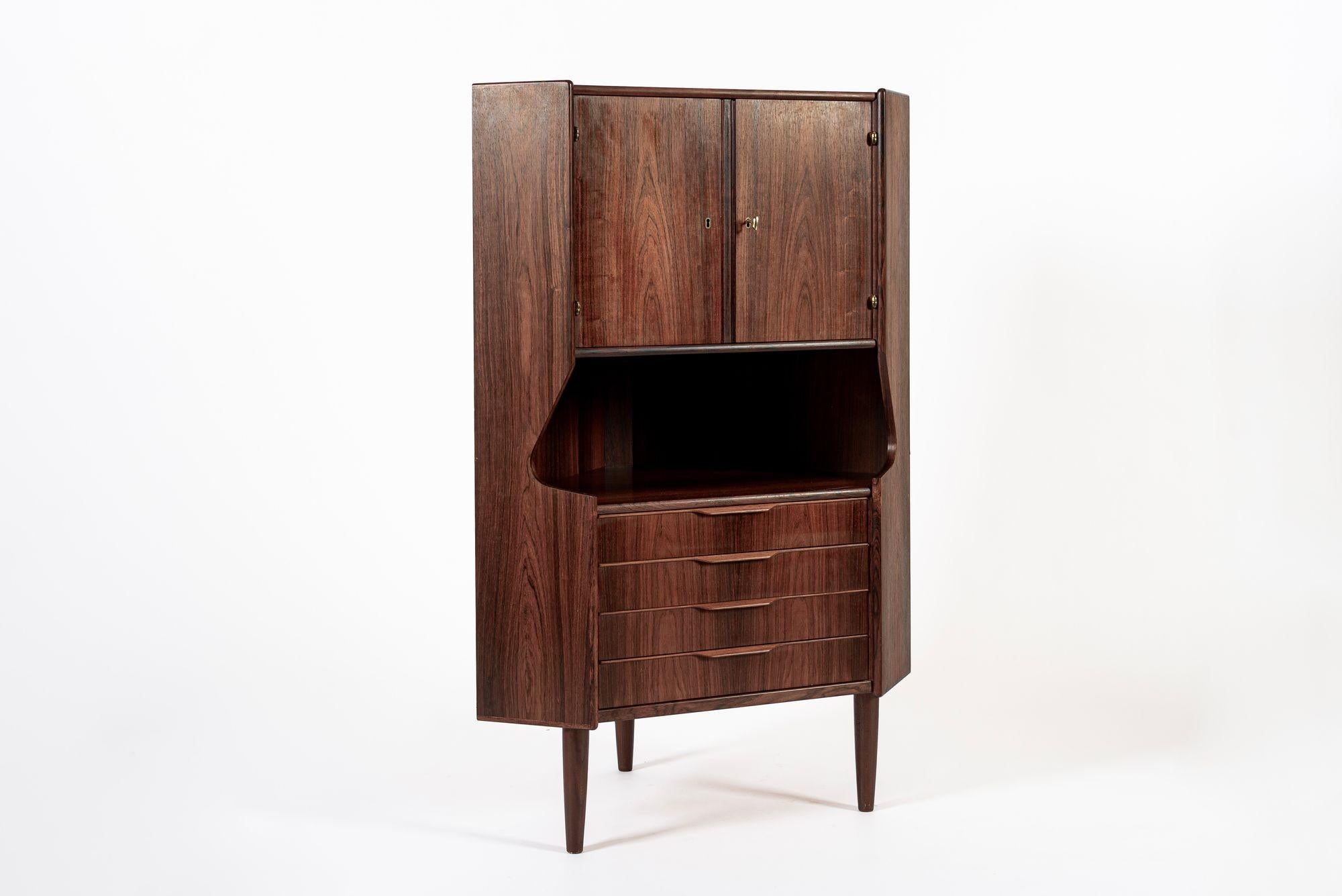 This exceptional vintage mid century Danish modern rosewood corner bar cabinet by Gunni Omann for Omann Jun (attr.) was made in Denmark circa 1960. The classic Scandinavian design has clean, elegant lines and is well-crafted from rosewood with