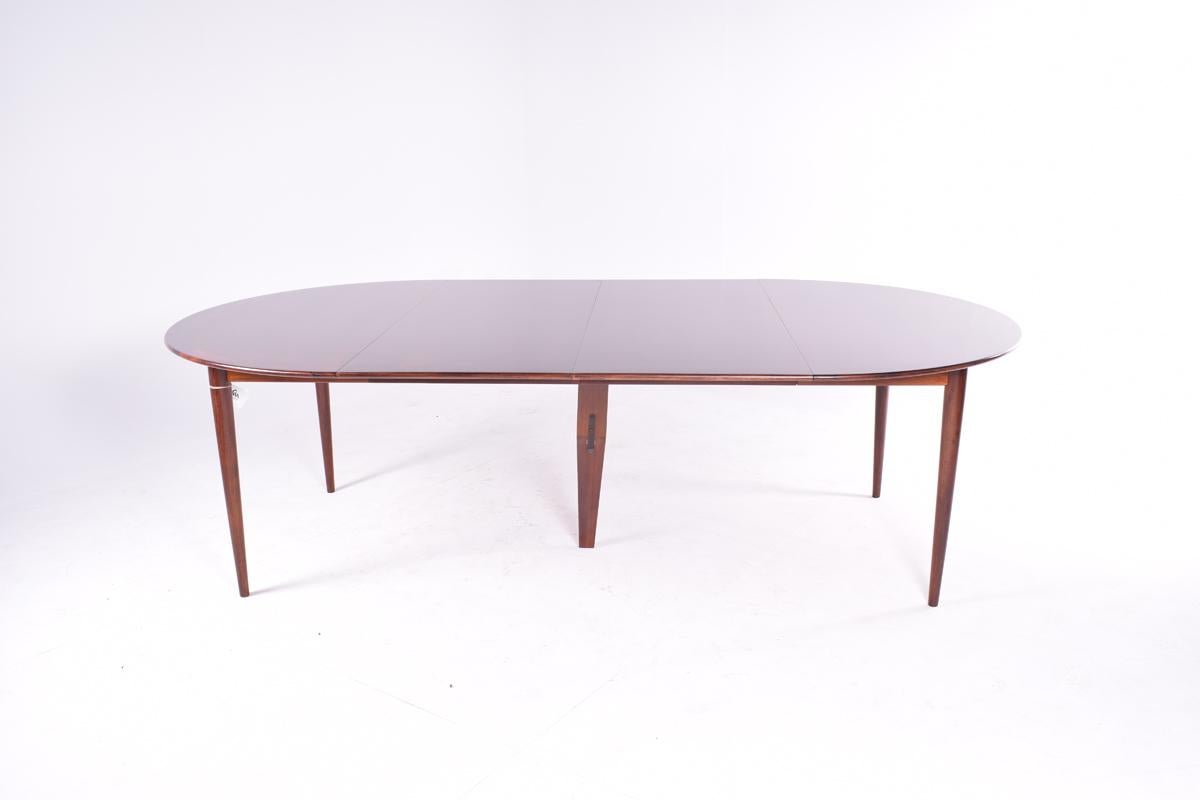 Grete Jalk dining table manufactured by Poul Jeppesen in the 1960s in Denmark. The rosewood frame detail, the leg joinery, and the extra leg for support when open, reflect the quality of the design and represent some of it´s major details, so as the