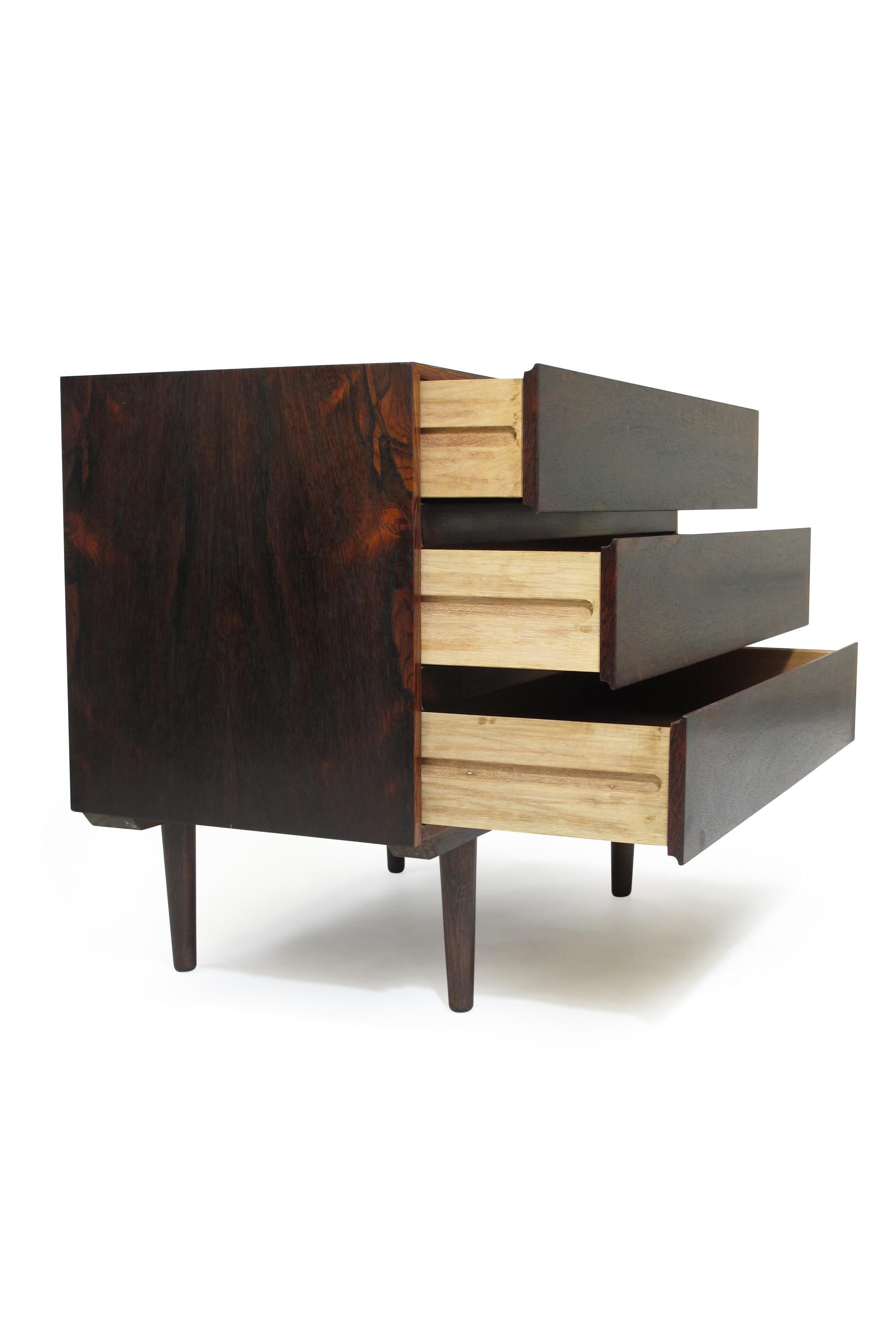 Three-drawer dresser crafted from rich, dark rosewood with bookmatched grain and set on tapered legs. Finely restored.