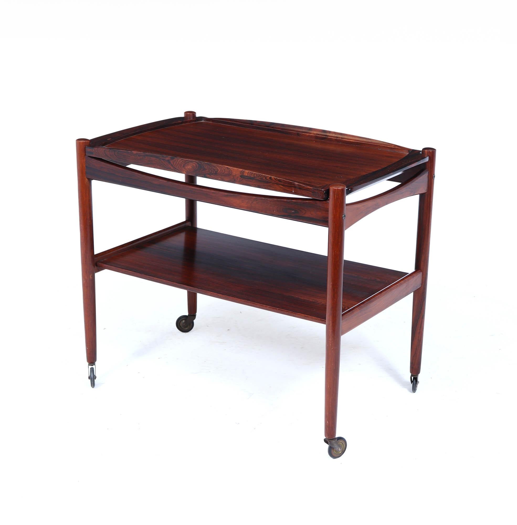 A beautifully crafted Danish rosewood drinks trolley from the 1960s, showcasing the refined minimalism of Scandinavian modern design. Constructed in richly grained rosewood with a warm, dark reddish tone, this elegant two-tier trolley features a