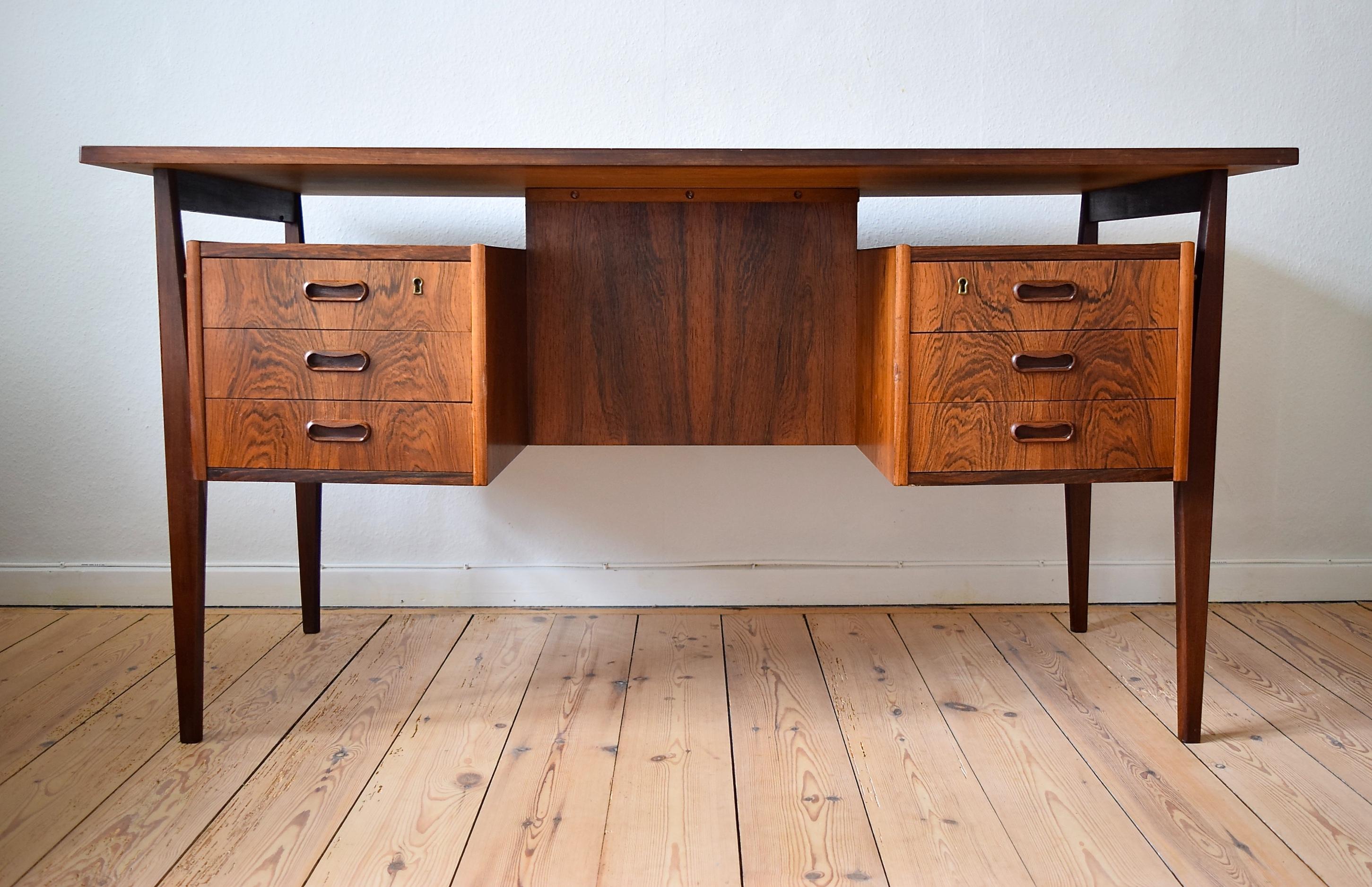 - Rosewood 'floating top' desk manufactured in Denmark in the 1960s
- Desk features six drawers on the front, two lockable
- Has a full-length shelf section on the rear side
- Top shows a strong rosewood grain pattern throughout
- Design of the