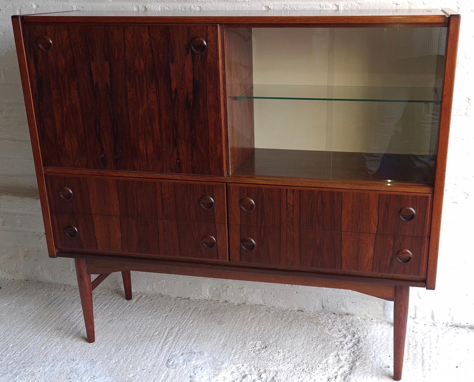Midcentury Danish rosewood highboard / sideboard / drinks cabinet, circa 1960s

Top half consists of a drop down drinks cabinet, and cupboard with glass shelf and two sliding glass doors for glasses. Below, this is 4 x good sized drawers, all