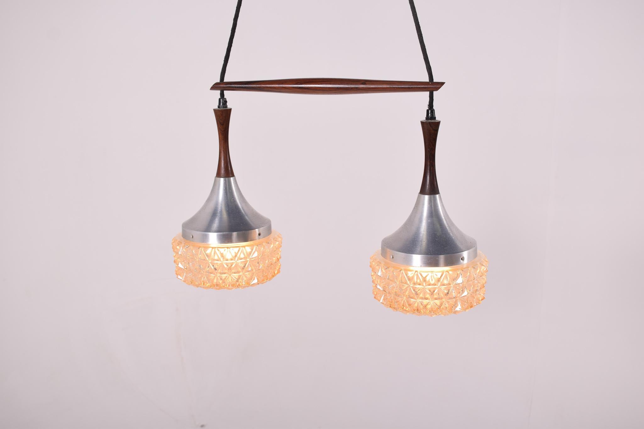Danish modern double pendant features by aluminium and is suspended by a sculpted piece of solid rosewood. Two lovely hammered glass. The length of the pendants can be adjusted.