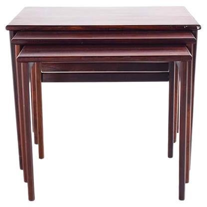 This set of Mid-Century nesting tables is a fine example of the elegance and practicality that characterizes Danish design. Made from rich rosewood, each table boasts a lustrous finish that highlights the natural beauty and deep, swirling grain