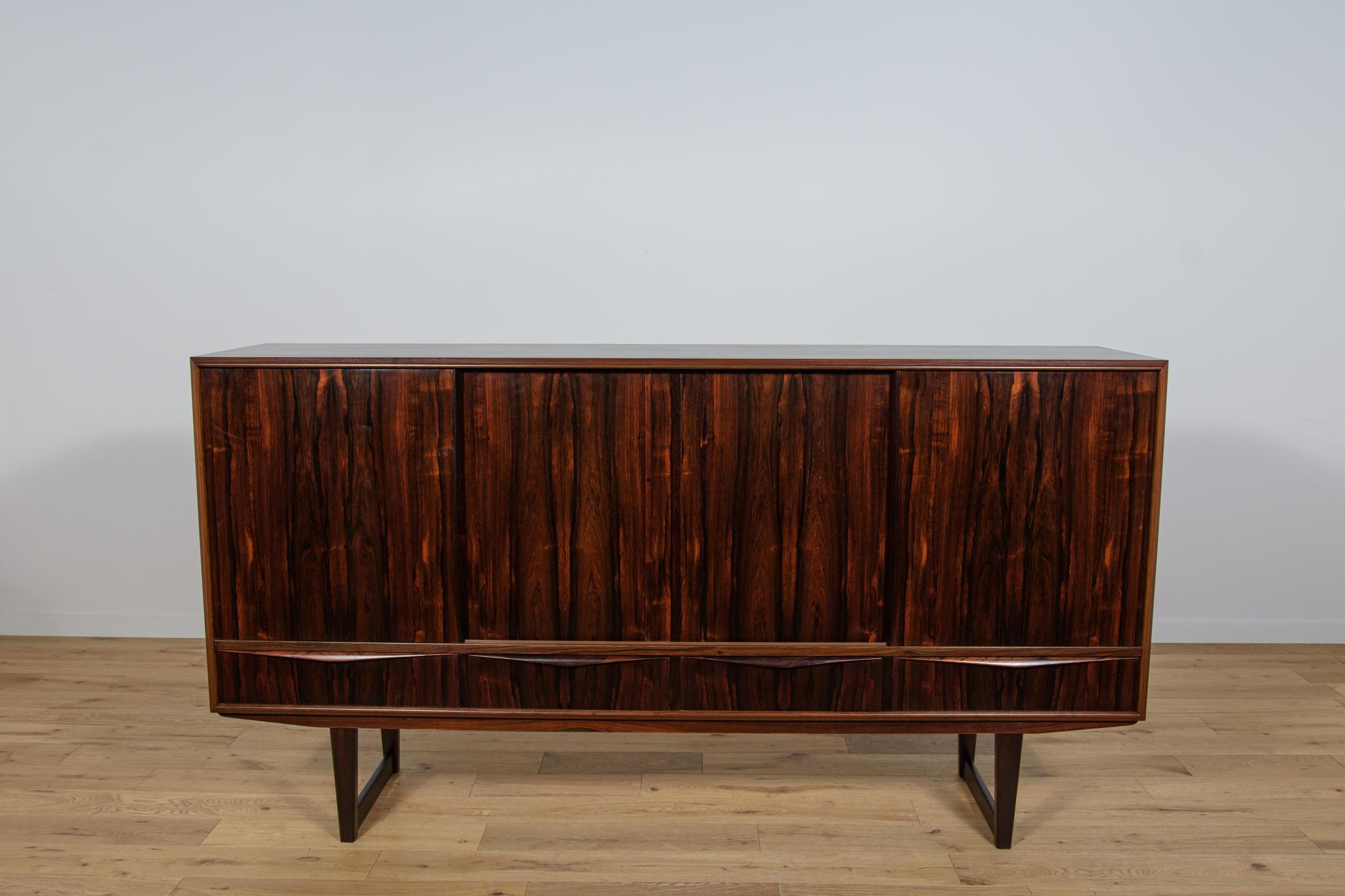 Credenza danese in palissandro disegnata da EW Bach per Sejling Skabe negli anni '60. La credenza ha quattro ante scorrevoli nella parte superiore e quattro cassetti nella parte inferiore. Nella parte superiore si trovano scaffali, una zona bar e