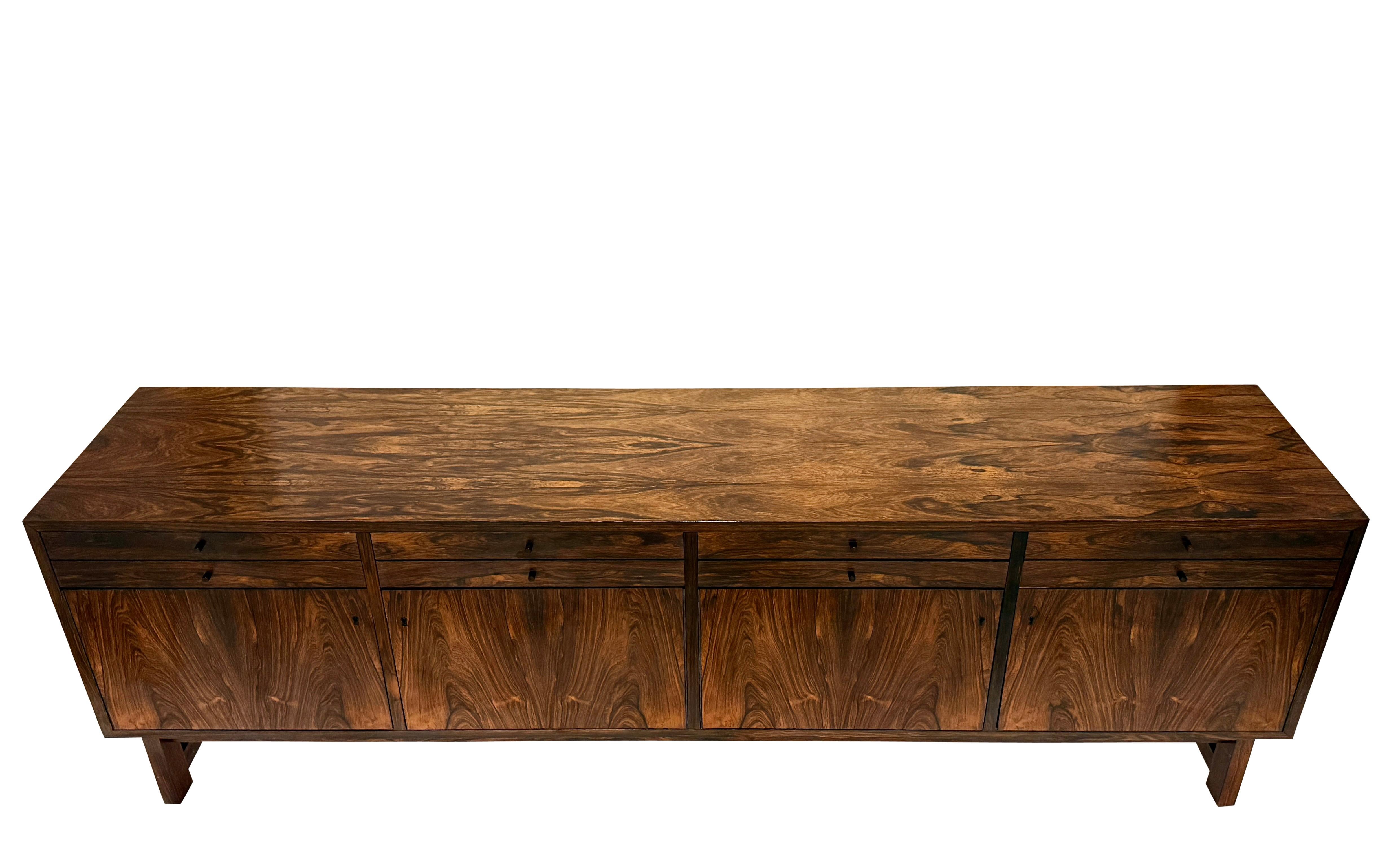 Un'eccezionale credenza moderna di metà secolo progettata e realizzata da Riis Antonsen in Danimarca. Questo pezzo lungo ed elegante mette in mostra le ricche venature del palissandro, splendidamente abbinate alle quattro ante del mobile. La