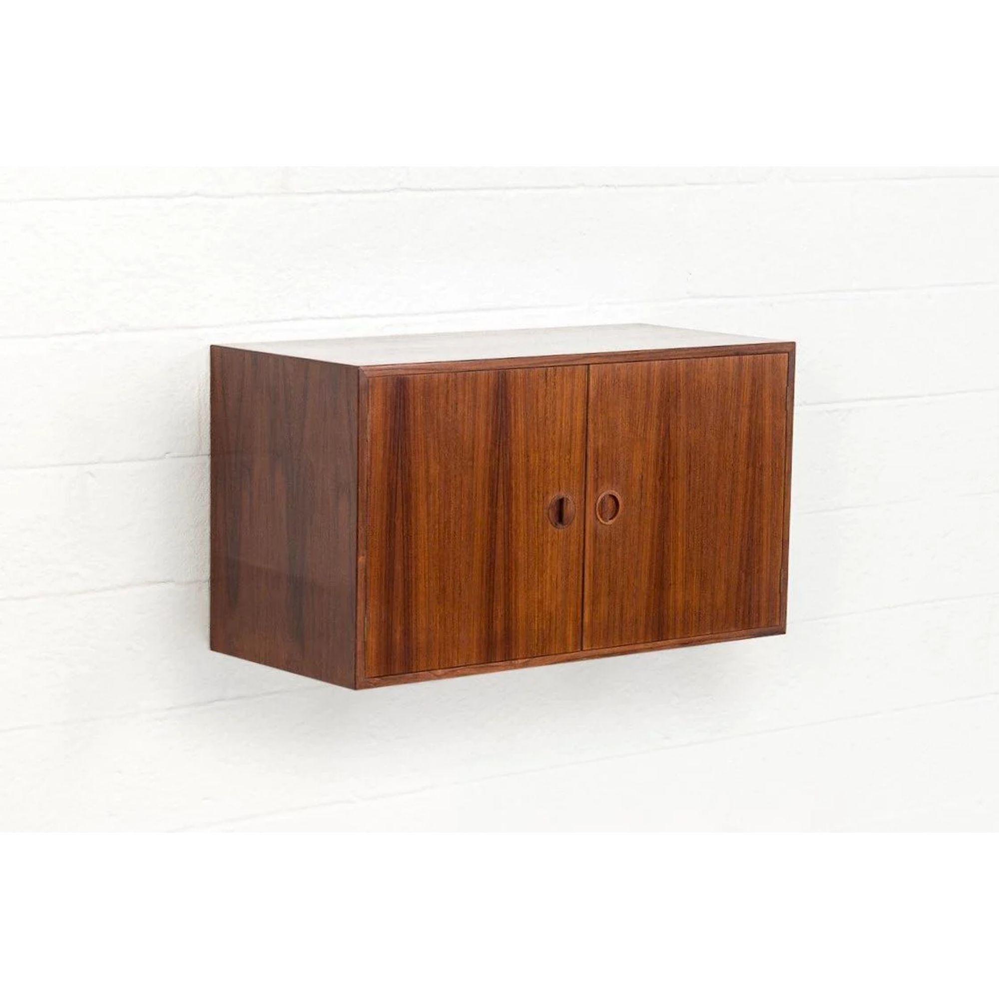 This vintage Mid-Century Modern Hansen & Guldborg wall-mounted cabinet, floating shelf or media console made in Denmark circa 1965 has a Classic Danish modern design with clean, Minimalist lines. Well constructed from rosewood the cabinet features