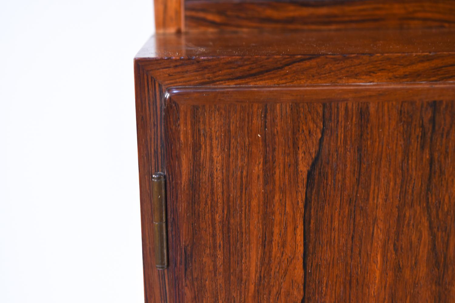 A Danish midcentury wall unit by Omann Jr. A double bookcase sits upon a cabinet beneath providing ample storage, both for display and hidden. This beautiful piece with bookmatched rosewood will be the highlight of any wall.