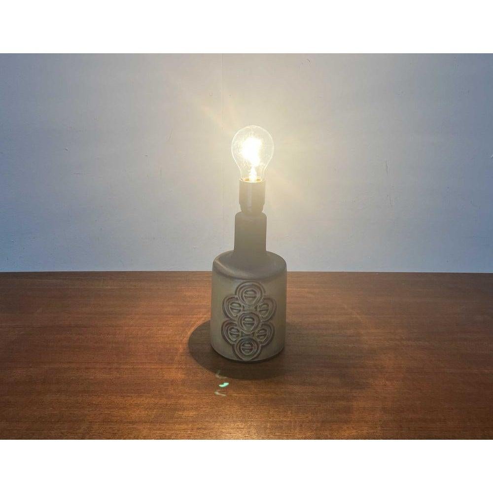 Lampe de table en céramique du fabricant danois Frank Keramik des années 60.

Un design danois traditionnel. La base en céramique est ornée d'une décoration frappante à l'avant et à l'arrière. Le câble sort par un trou situé à l'arrière. Des