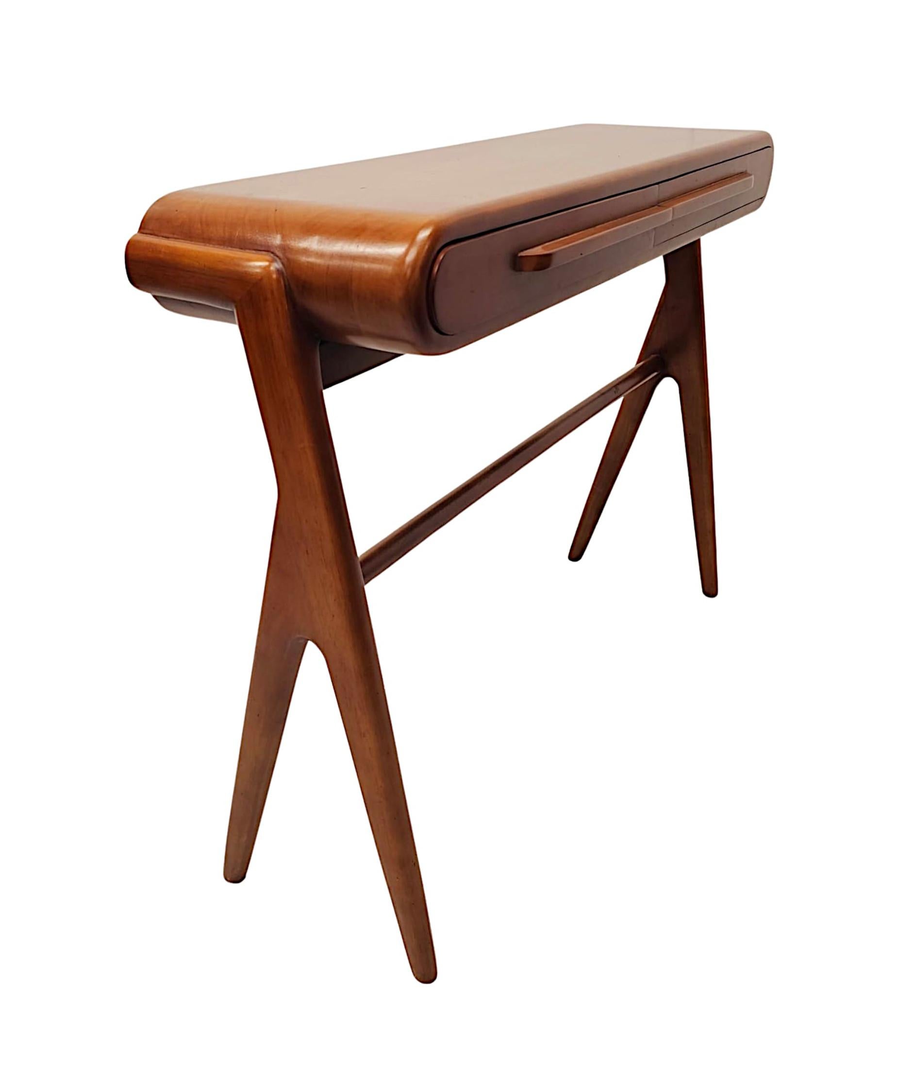 A stunning Mid-Century Danish style finely carved walnut console or side table of exceptional quality with fabulously rich patination and grain.  The moulded, well figured, curvilinear top is raised over a two drawer frieze fitted with beautifully