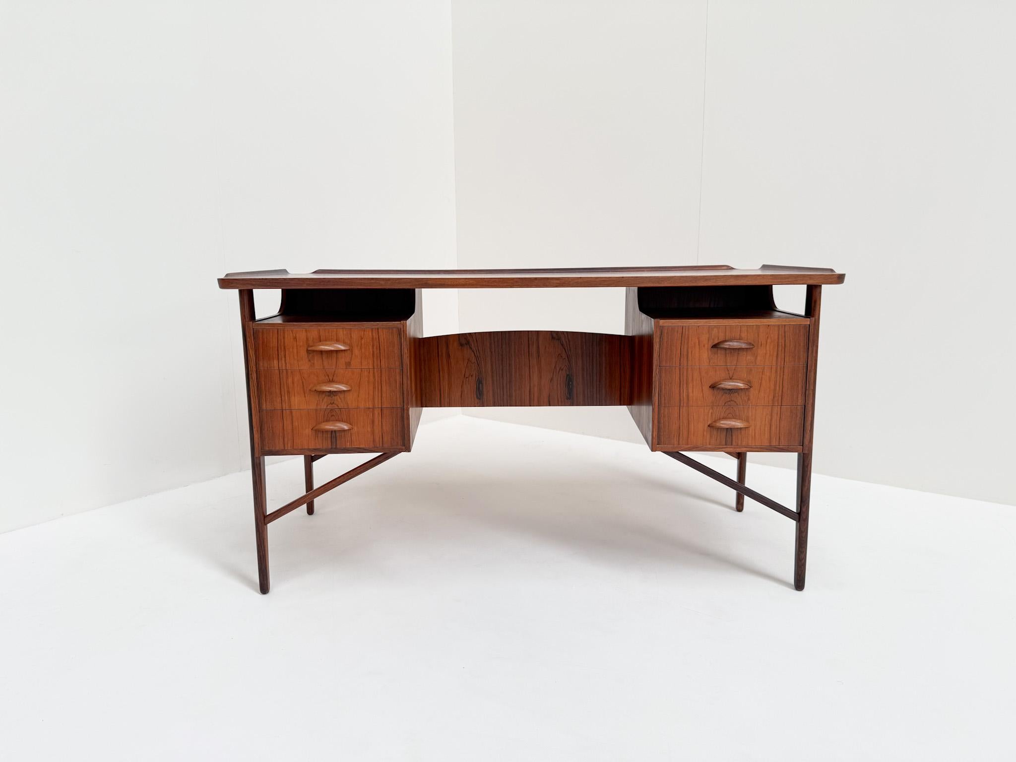 Un magnífico escritorio danés de época diseñado por Svend Aage Madsen, que data de la década de 1960. Fabricada en madera de palisandro, presenta una calidad excepcional y un diseño escandinavo atemporal. La parte superior tiene una forma