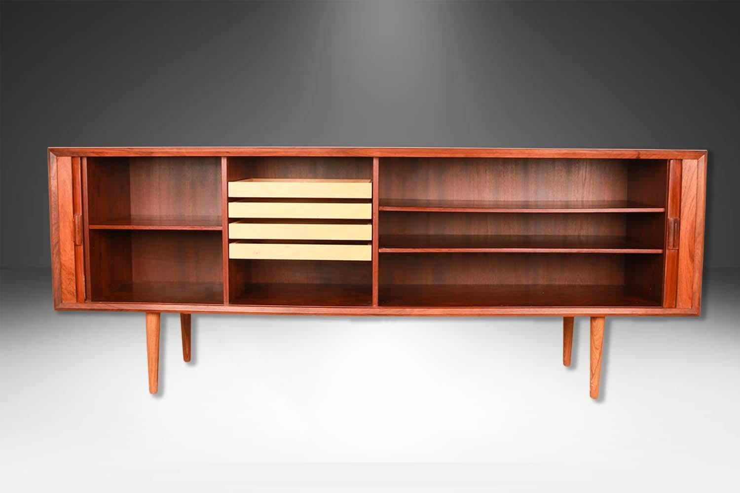 Remarkable and stunning credenza by Famous designer Svend Larsen for Faarup Mobelfabrik made in Denmark. This Danish Modern credenza, Media Cabinet is beautifully embellished with bands of teak running perpendicular to the main surface. Precisely