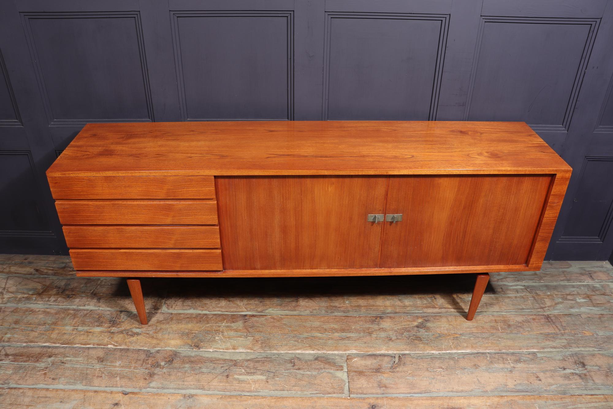H.W KLEIN DESIGN SIDEBOARD PRODUCED BY BRAMIN.
Designed in the 1960’s by Henry Walter Klein and produced by Bramin, this early example in teak has two sliding tambour doors with shelves behind and four drawers to the left with integrated handle