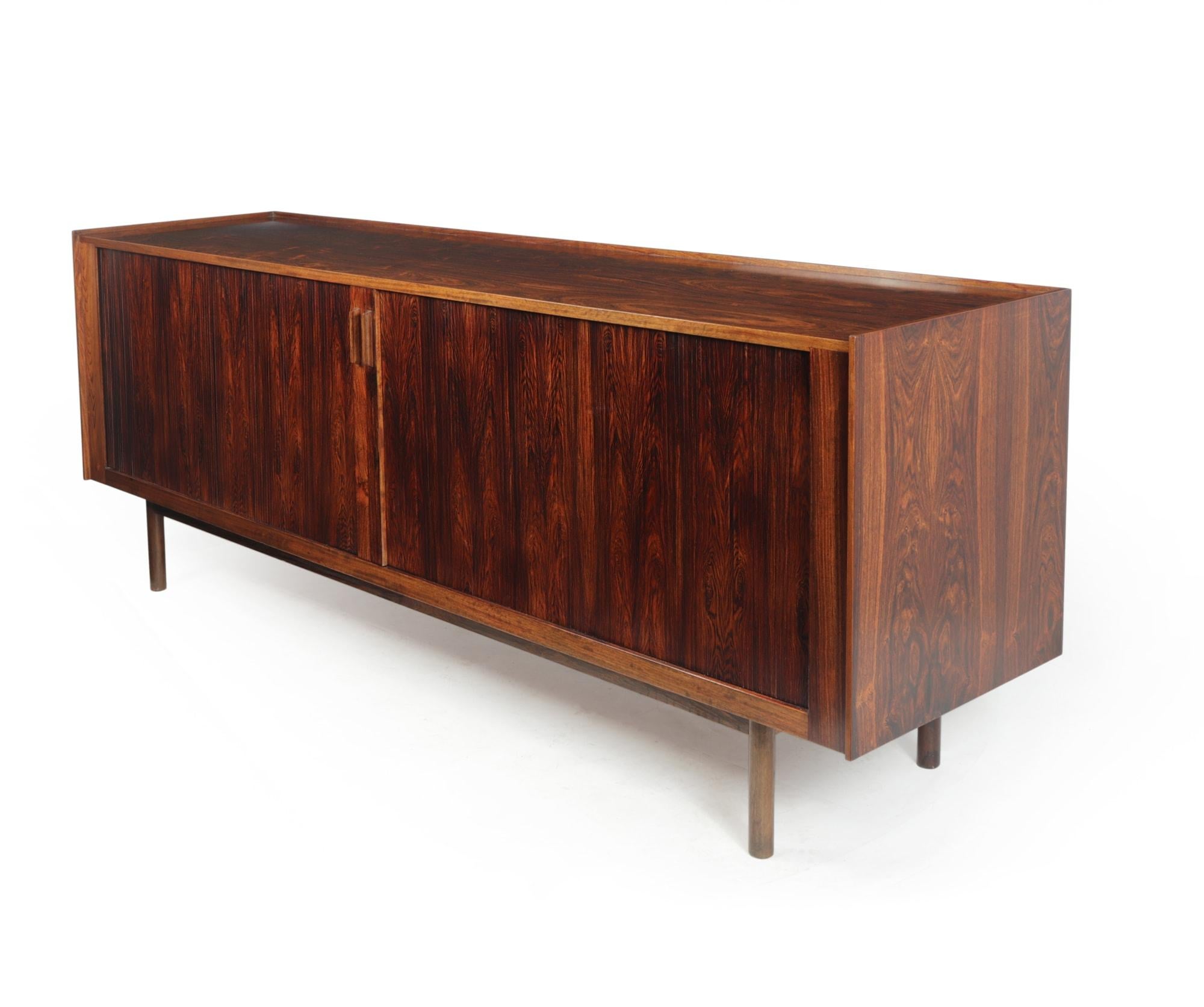 A stunning sideboard designed by Ib Kofod Larsen and produced in Denmark in the 1960’s, it has two sliding tambour doors to reveal adjustable shelves and internal drawers, the top has a ‘lipped edge’ this all sits on four turned legs. The Sideboard