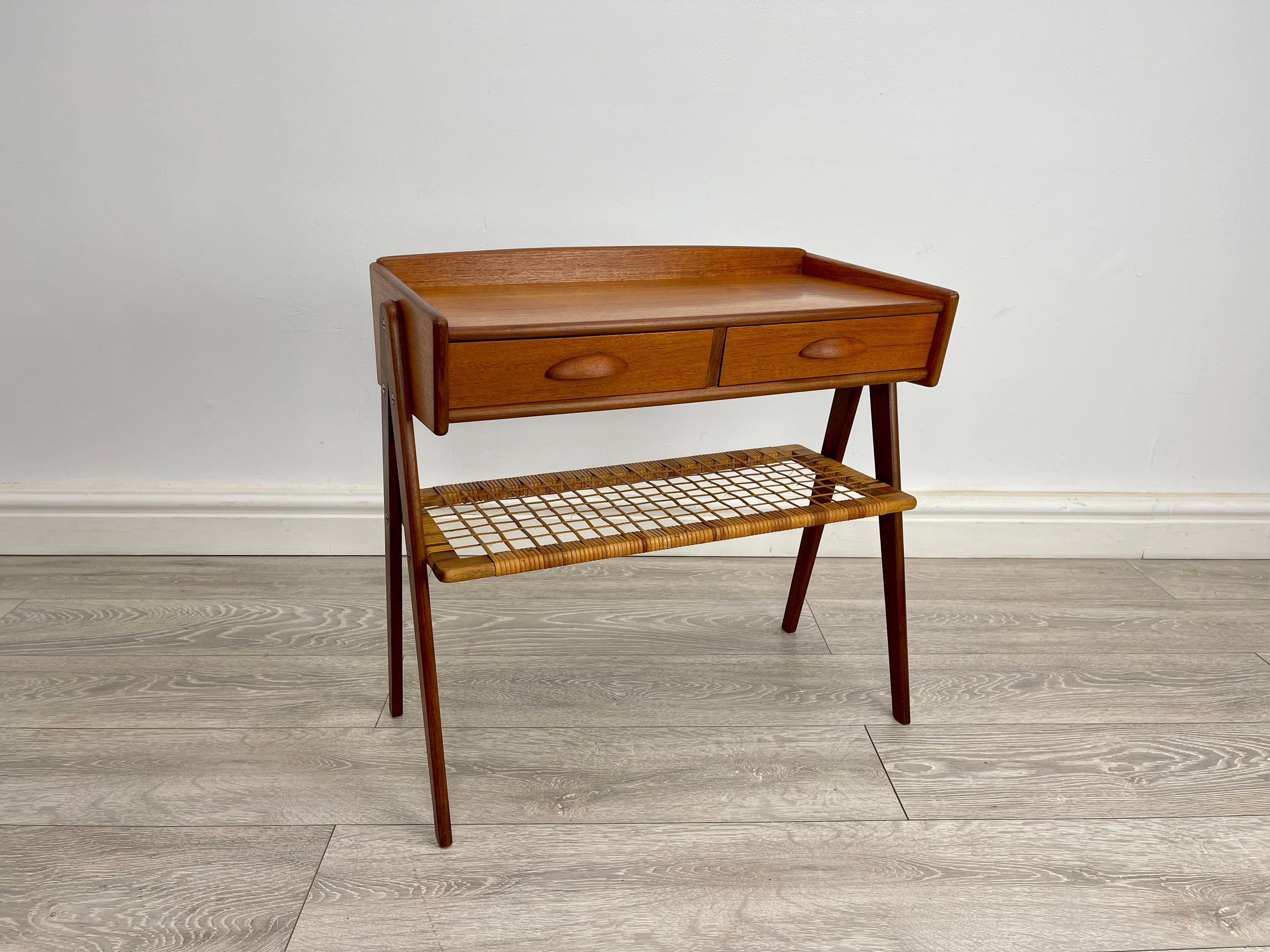 SIDE TABLE 
Stunning midcentury Danish teak and rattan side table designed by Soren Rasmussen circa 1960s. 
The side table has stunning grain throughout , stands on elegant v shaped leg , there’s two small drawers with rattan shelf below .

Height -