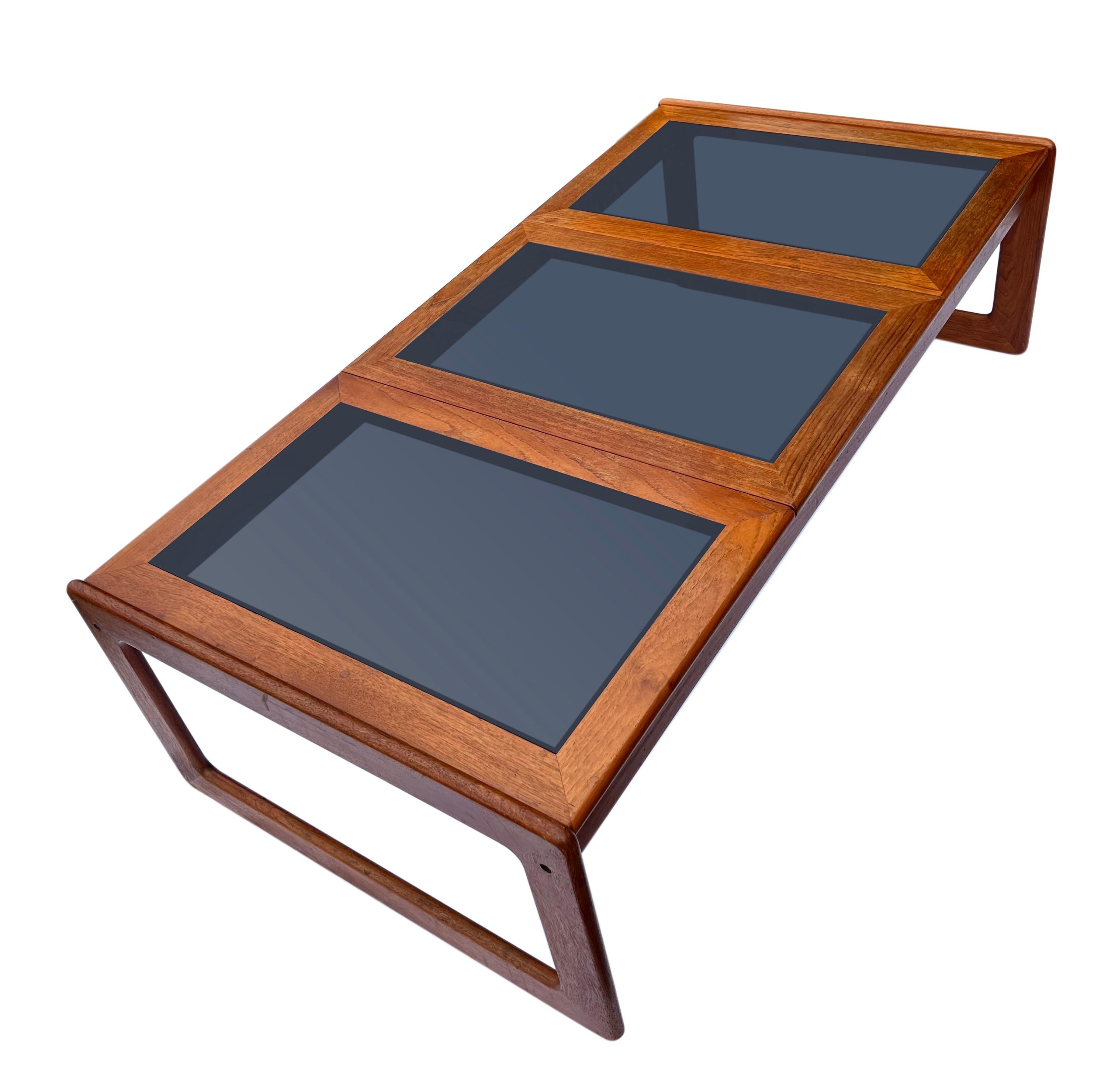Exceptional mid century Danish teak coffee table with smoked glass by Komfort, made in Denmark. 

This impressive table features three large smoked glass insert panels. The teak has been well cared for and has maintained its original beauty.