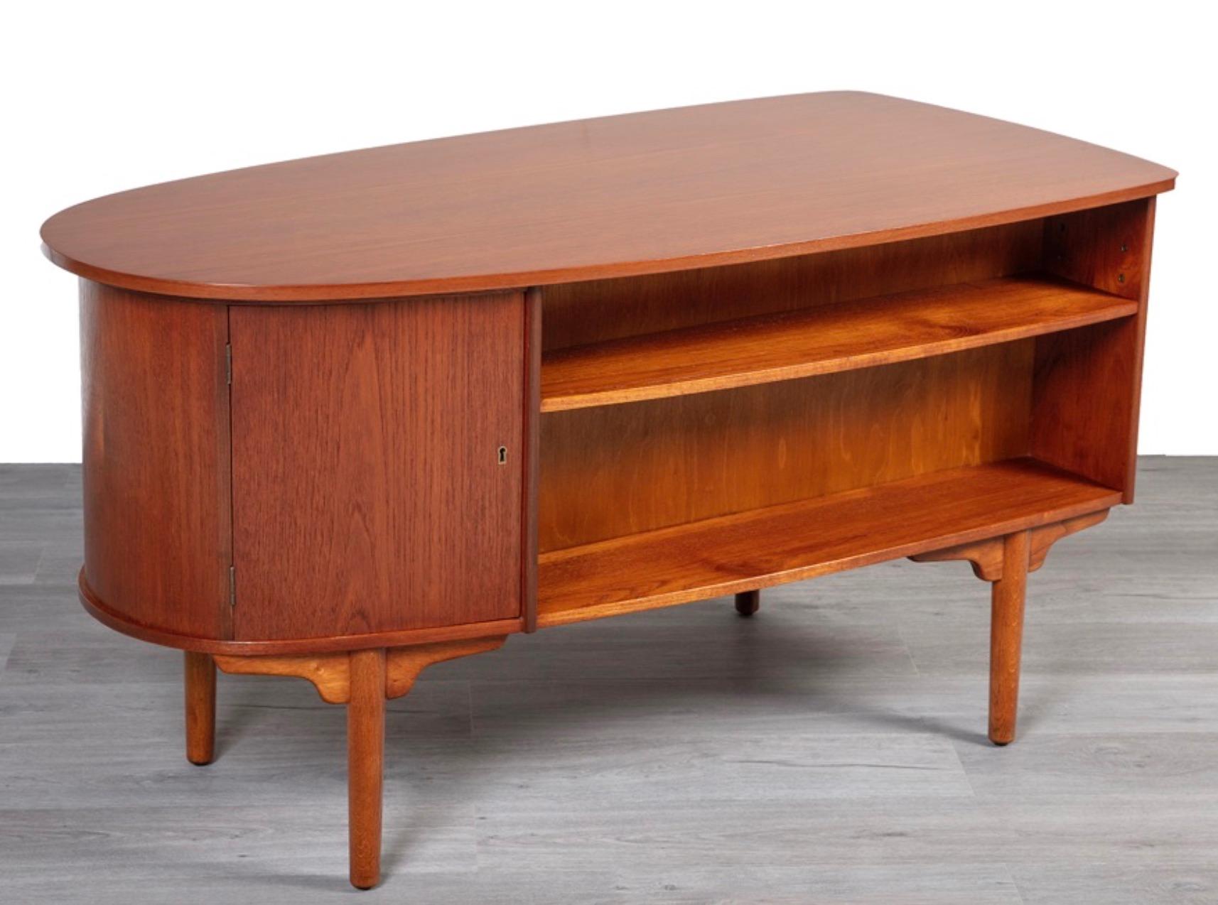 Mid-century Danish teak desk by H.P. Hansen for Randers designed in the shape of a ball and comprised of four solid wood dovetail drawers accented by intricately carved handles. The main drawer and storage compartment with unique double-sided