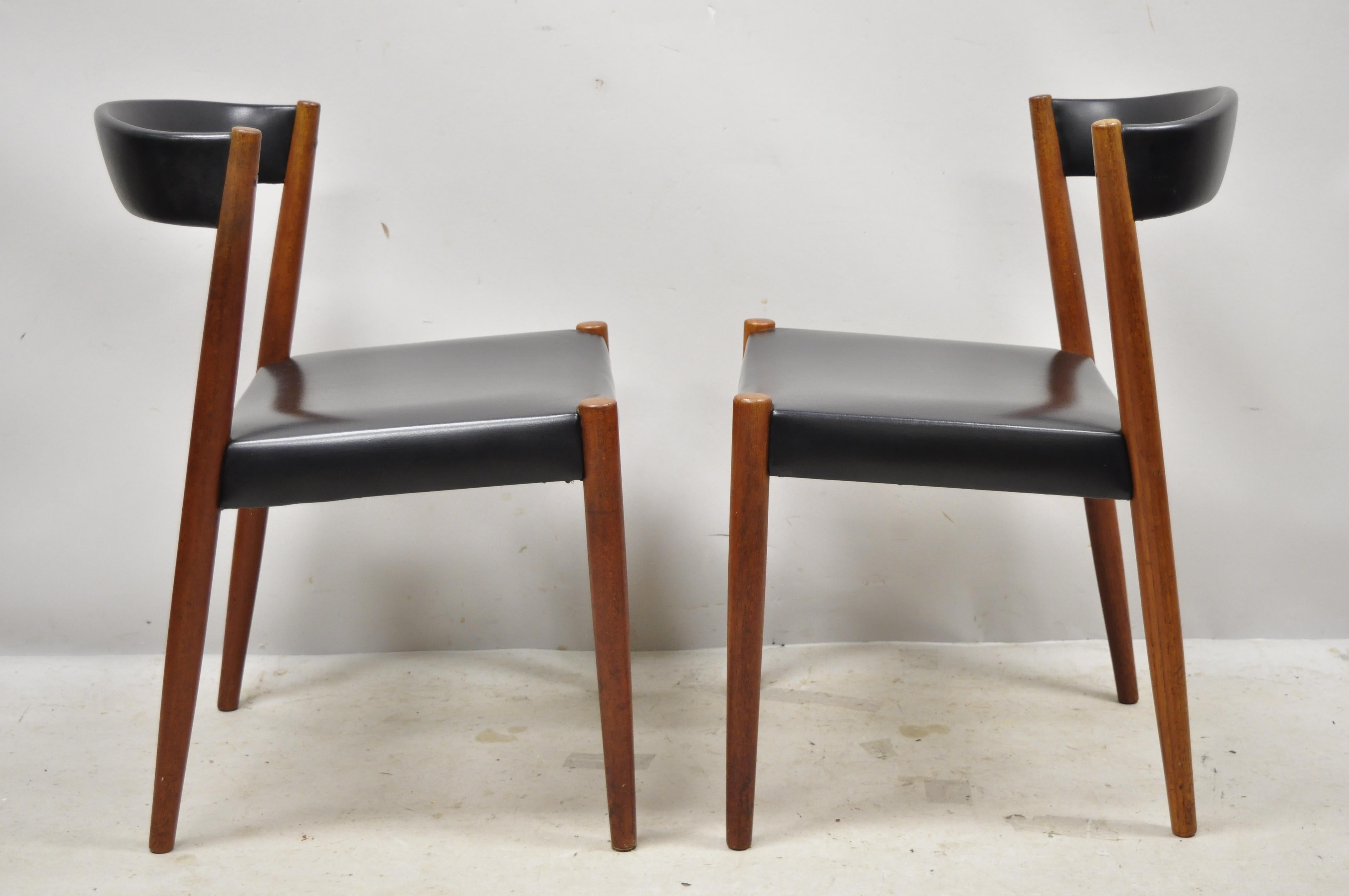 Midcentury Danish modern teak barrel back curved black vinyl dining side chairs - a pair. Item features original black upholstery, solid wood frame, beautiful wood grain, tapered legs, clean modernist lines, sleek sculptural form, circa mid-20th