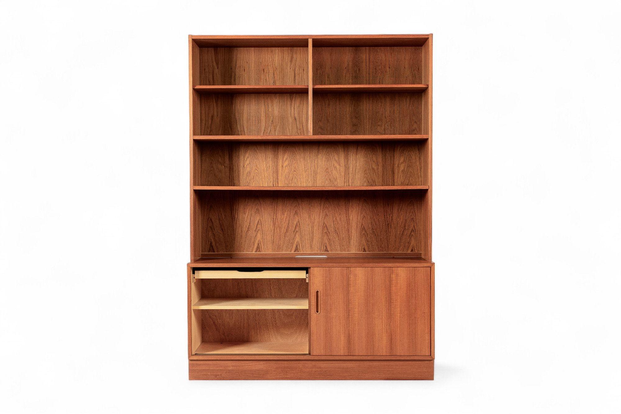 Esta librería vintage danesa moderna de dos piezas de teca de mediados de siglo, diseñada por Poul Hundevad para Hundevad & Co, se fabricó en Dinamarca hacia 1970. El diseño moderno escandinavo minimalista presenta líneas limpias y geométricas, y el