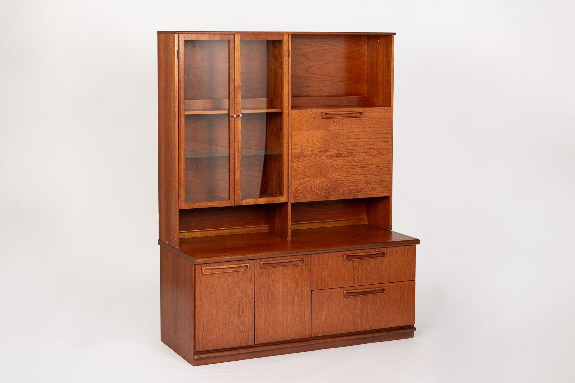 This vintage mid century modern step-back teak secretary bookcase or wall unit cabinet was made in Denmark in 1981. This beautiful cabinet is elegantly proportioned with clean, minimalist lines and is well-crafted from teak wood with a rich, warm