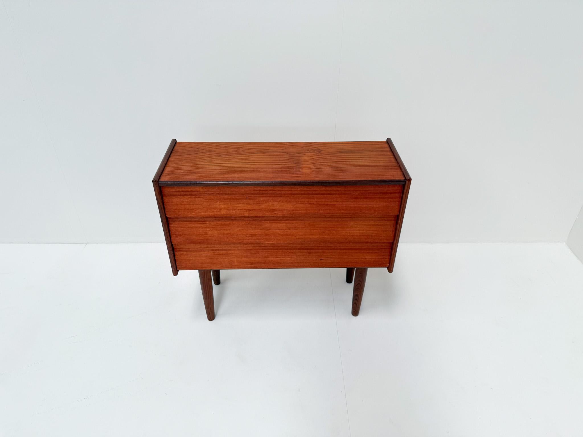 Elegant mid-century Danish chest of drawers crafted in the 1960s, featuring a sleek teak body with three drawers and tapered legs. This piece showcases the refined simplicity and functionality characteristic of Scandinavian modern design. The warm