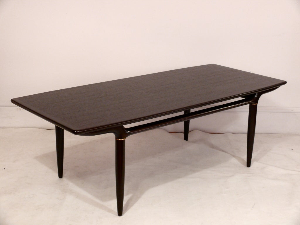 Beautiful elongated coffee table, made in Denmark. Amazing sculptural base with brass insets supports a beautifully grained rectangular top. Refinished in a deep chocolate. Perfect for any modern or transitional interior.