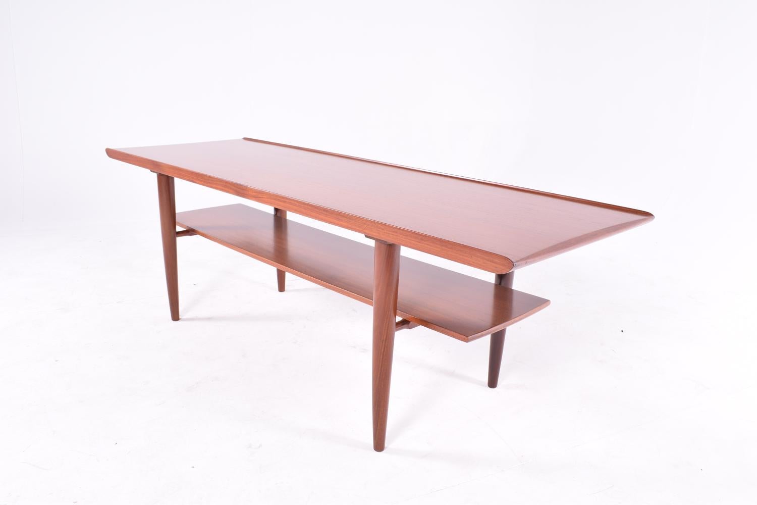 This midcentury coffee table is a beautiful addition to any modern living room. This piece from the 1960s combines delicate construction details with a straight and sleek design. The two levels allow for different usage, as you can combine different
