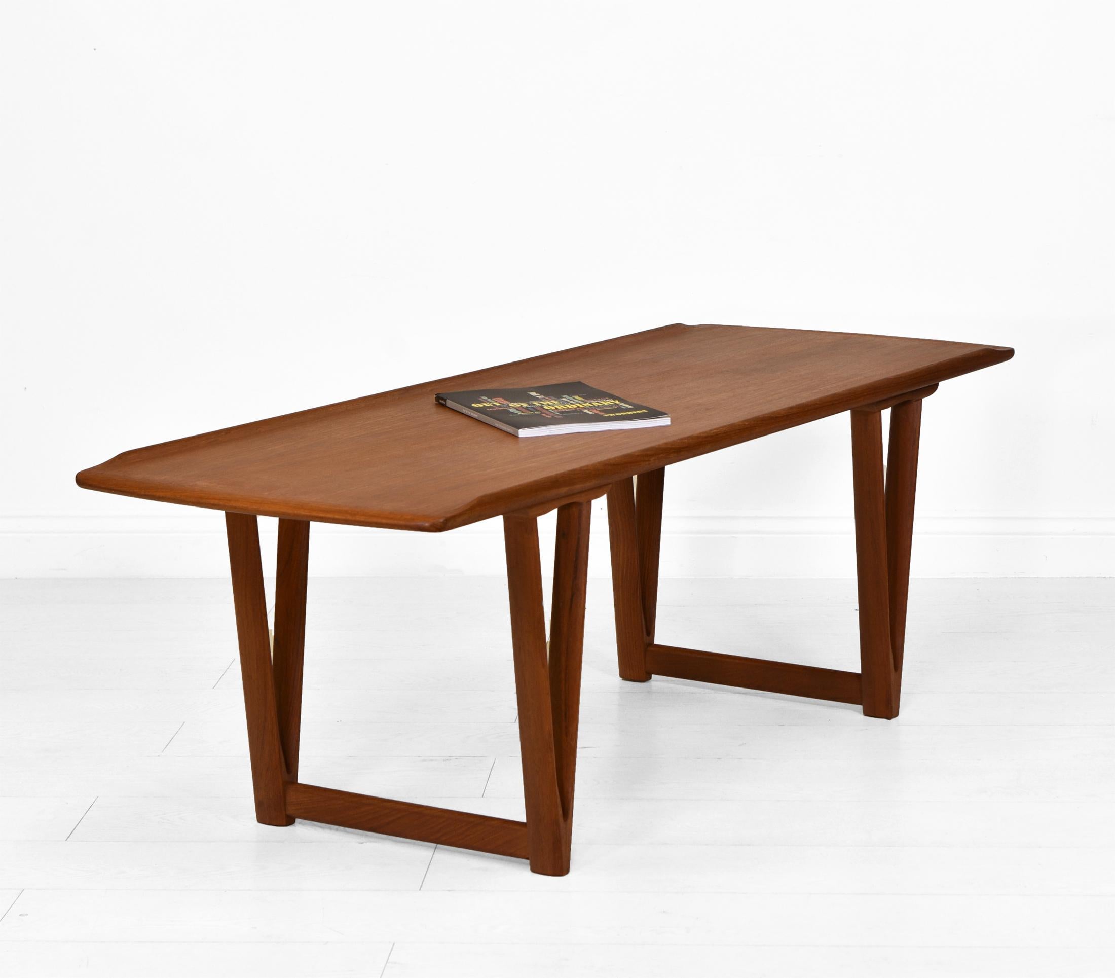 A mid century Danish teak coffee table attributed to Andreas Hansen. Circa 1960.

This stylish design table stands on V-shape supports and has a lipped top edge.

It is in very good condition for its age, the top has a matt finish and there are