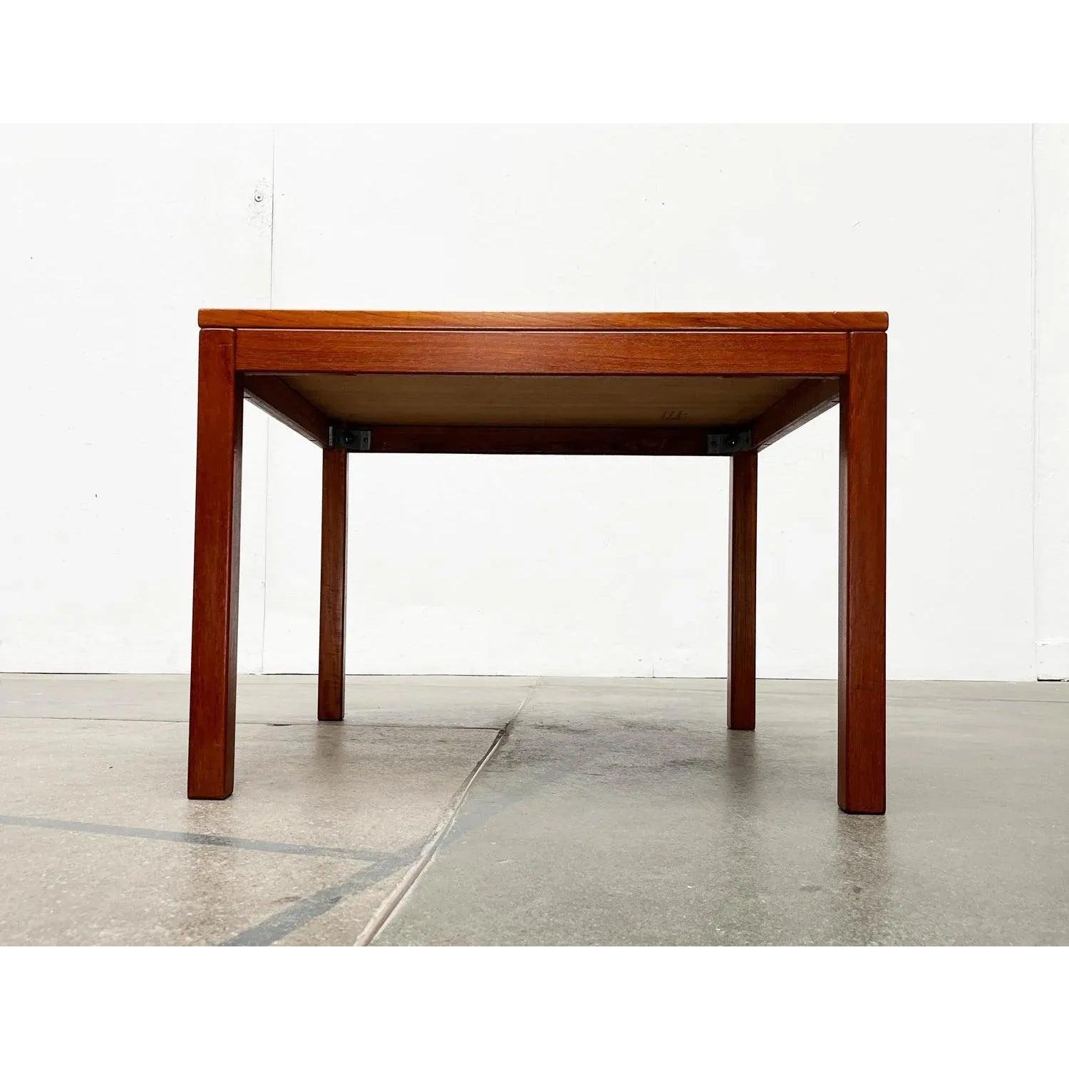 Square teak coffee table from the Danish manufacturer Vejle.

The frame consists of a frame made of solid teak wood. The plate is on top. The veneer on the table surface is applied in strips and shows a rich grain. The table is in very good