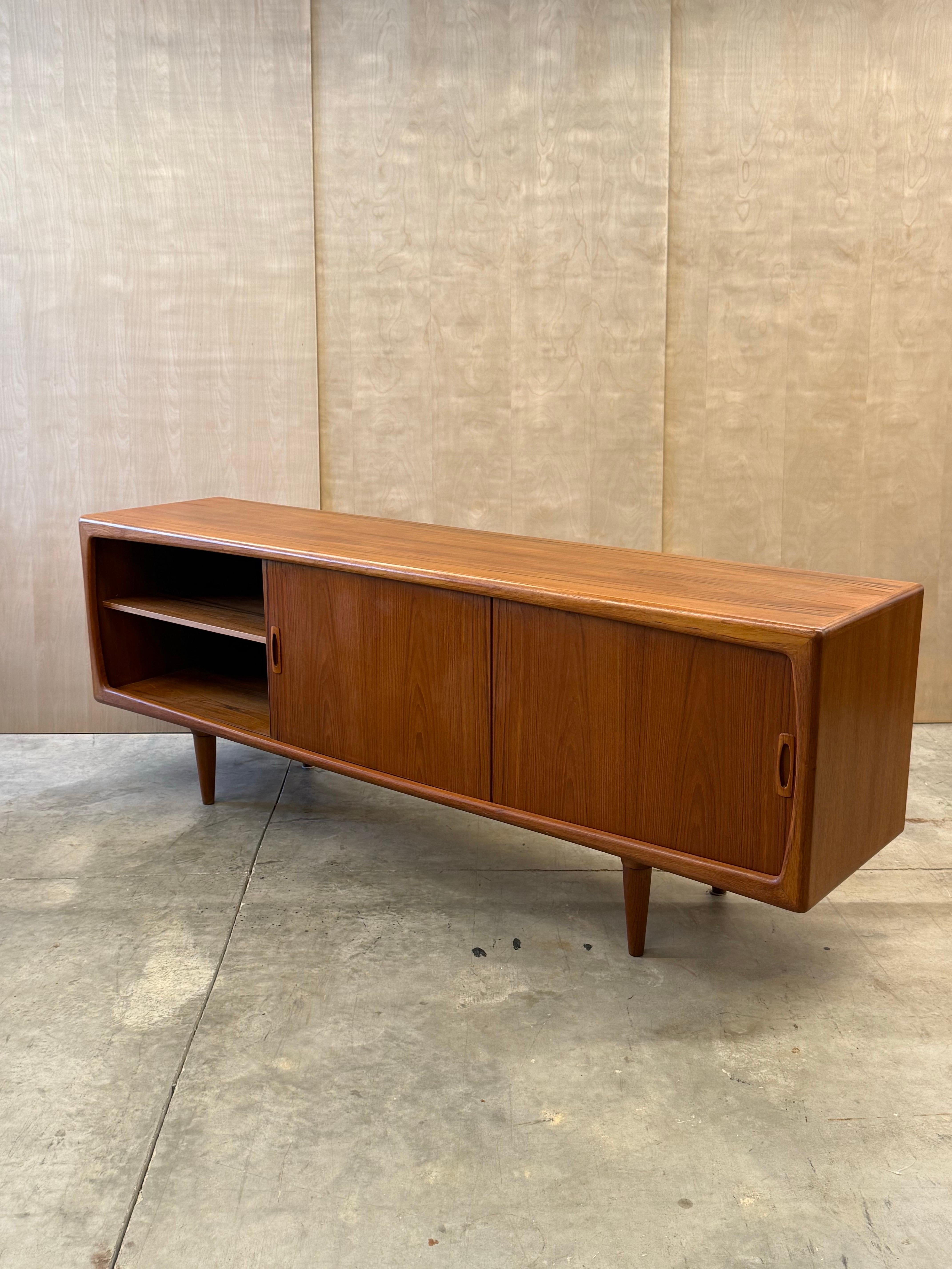 Large mid-century Danish credenza designed by H.P. Hansen, circa 1960s. Made from teak wood with fantastic storage potential and ample design elements to dote on.

The face of this piece consists of two smooth sliding teak panel doors flanked on