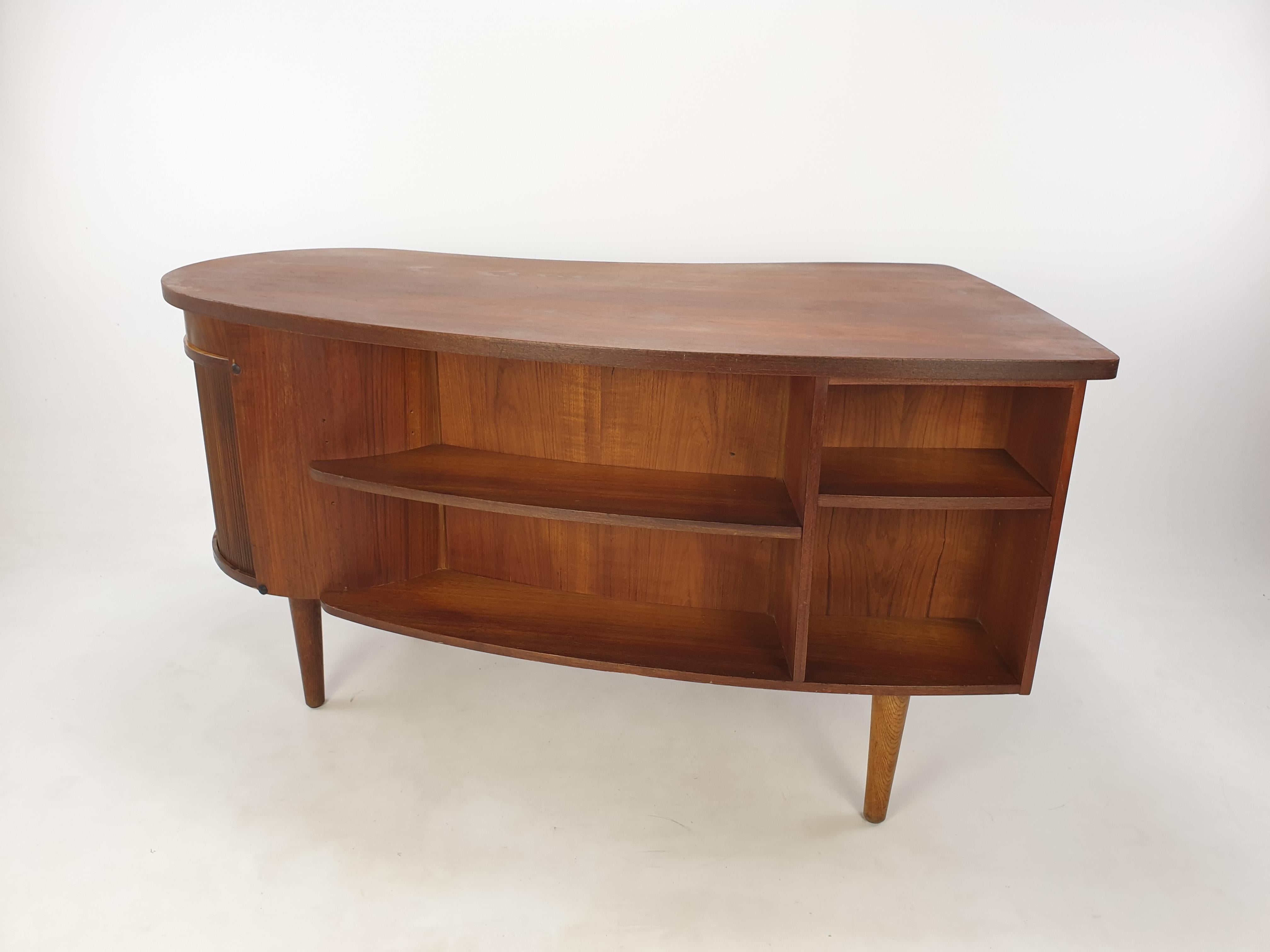 Beautiful mid century Danish desk with a lovely shaped top. Designed by Kai Kristiansen and fabricated by Feldballes Møbelfabrik in the 50's.

A cute circular storage section with a roll sliding door, inside a turning bar with etched