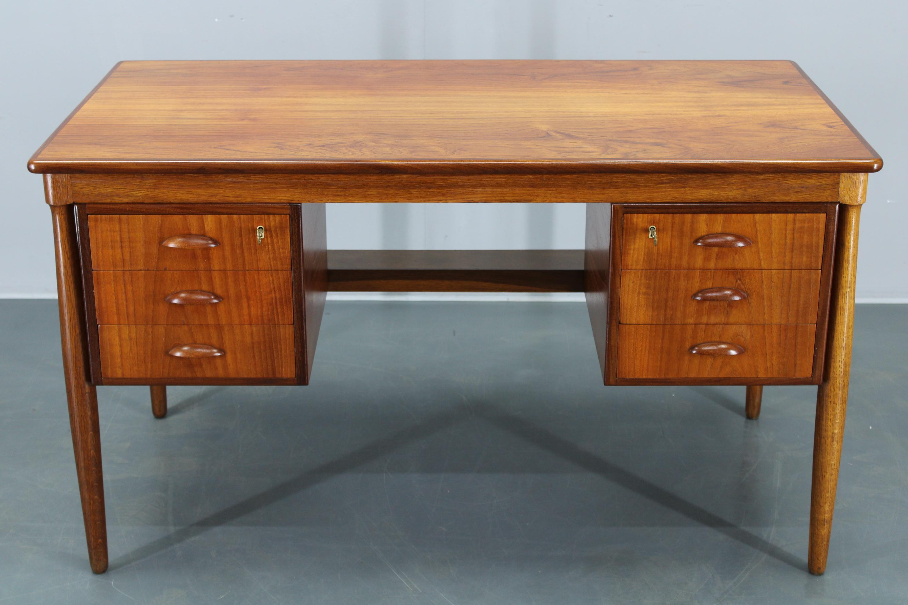 Scrivania danese vintage degli anni '60, realizzata con impiallacciatura di teak di alta qualità e teak massiccio. Questa scrivania a doppio piedistallo presenta sei cassetti con maniglie scolpite e linee classiche di metà secolo, che incarnano