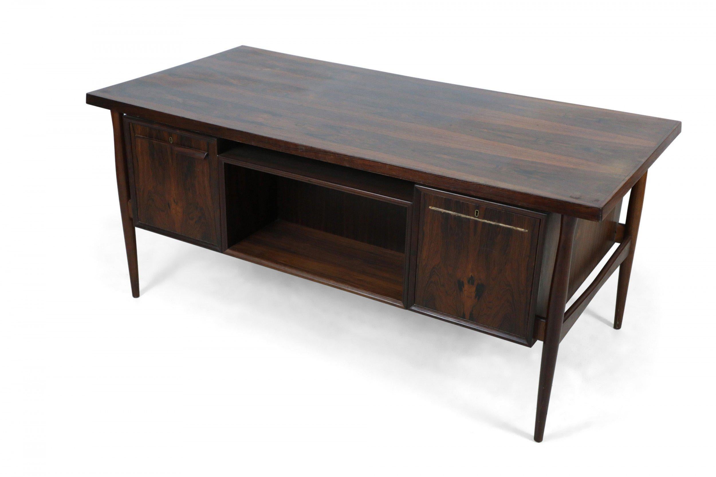 Danish mid-century teak office desk with six smaller drawers having shaped drawer pulls and the back having two large keyed drawers centering a vanity panel with a shelf, all supported on tapered legs.
  