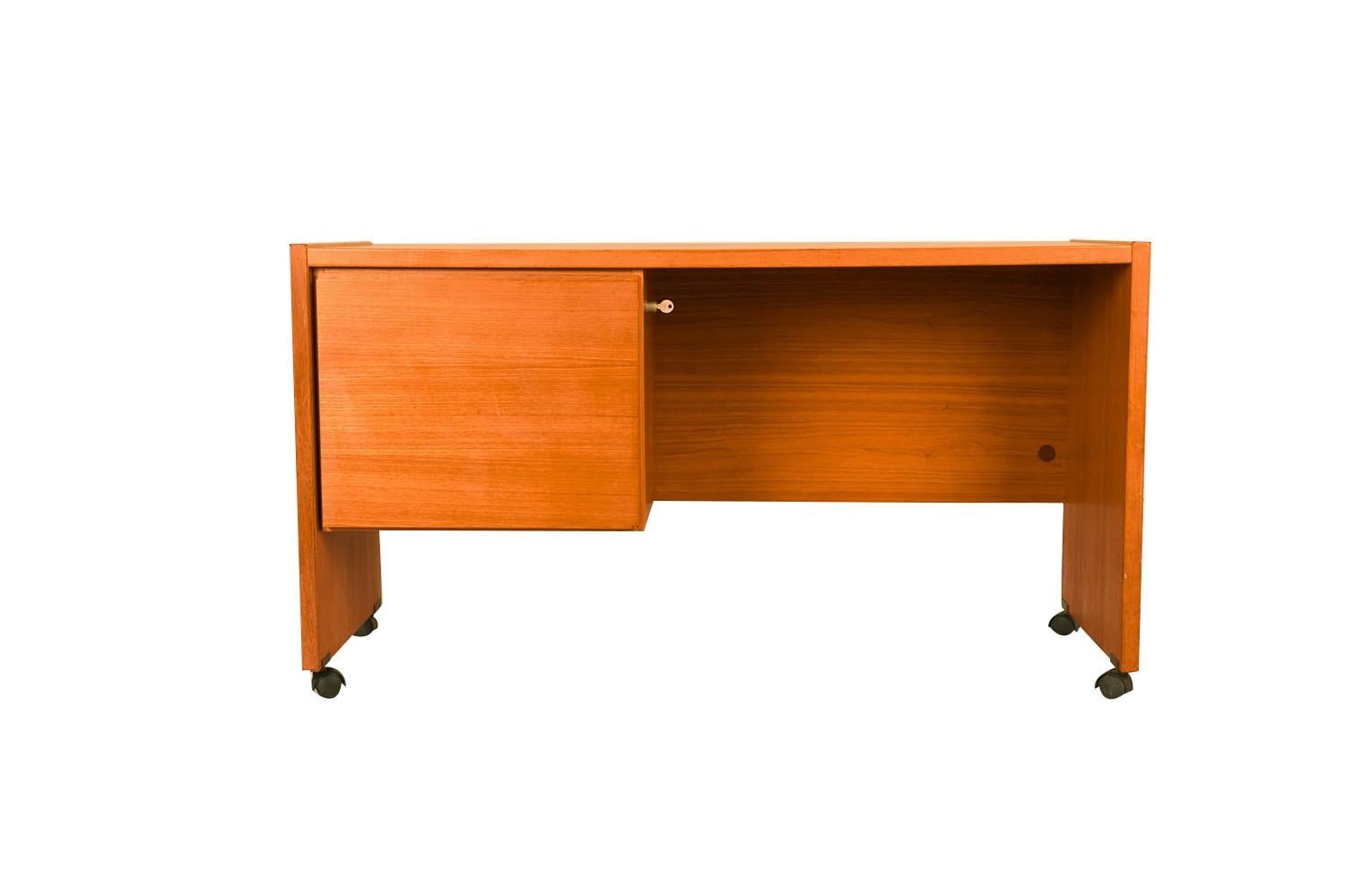A beautiful Danish modern mid century teak desk, crafted by Nordisk Andels-Eksport in Denmark. Features a rectangular top above one generously-sized filing drawer to the left, key is present, while the right side is open, with a fully finished back.