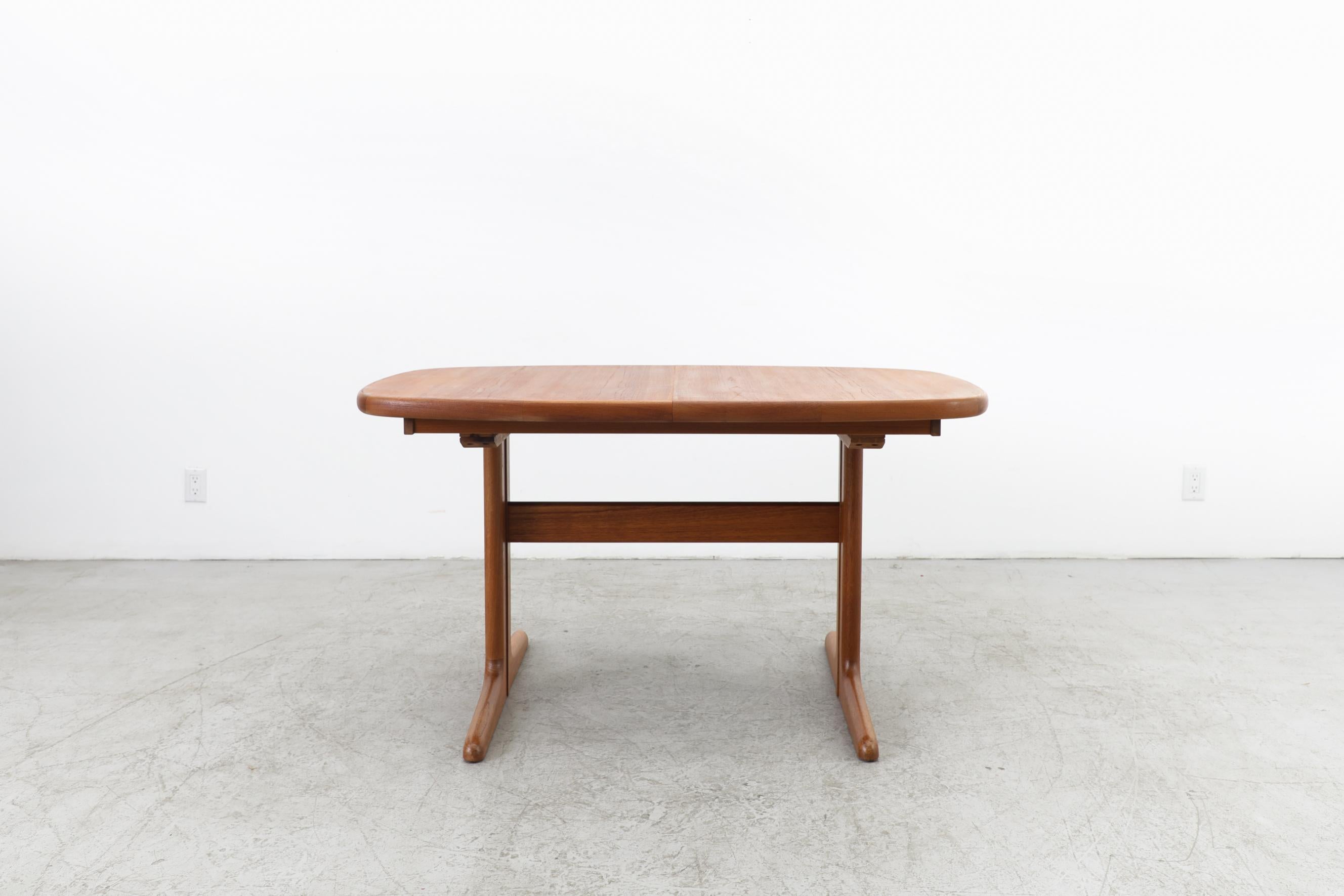 Mid-century 1970's Danish teak dining table with 2 leaves by Skovby Møbelfabrik. It is a 70's Danish oval-ish teak dining table with double T-shaped legs that has 2 leaves that measures 19.625