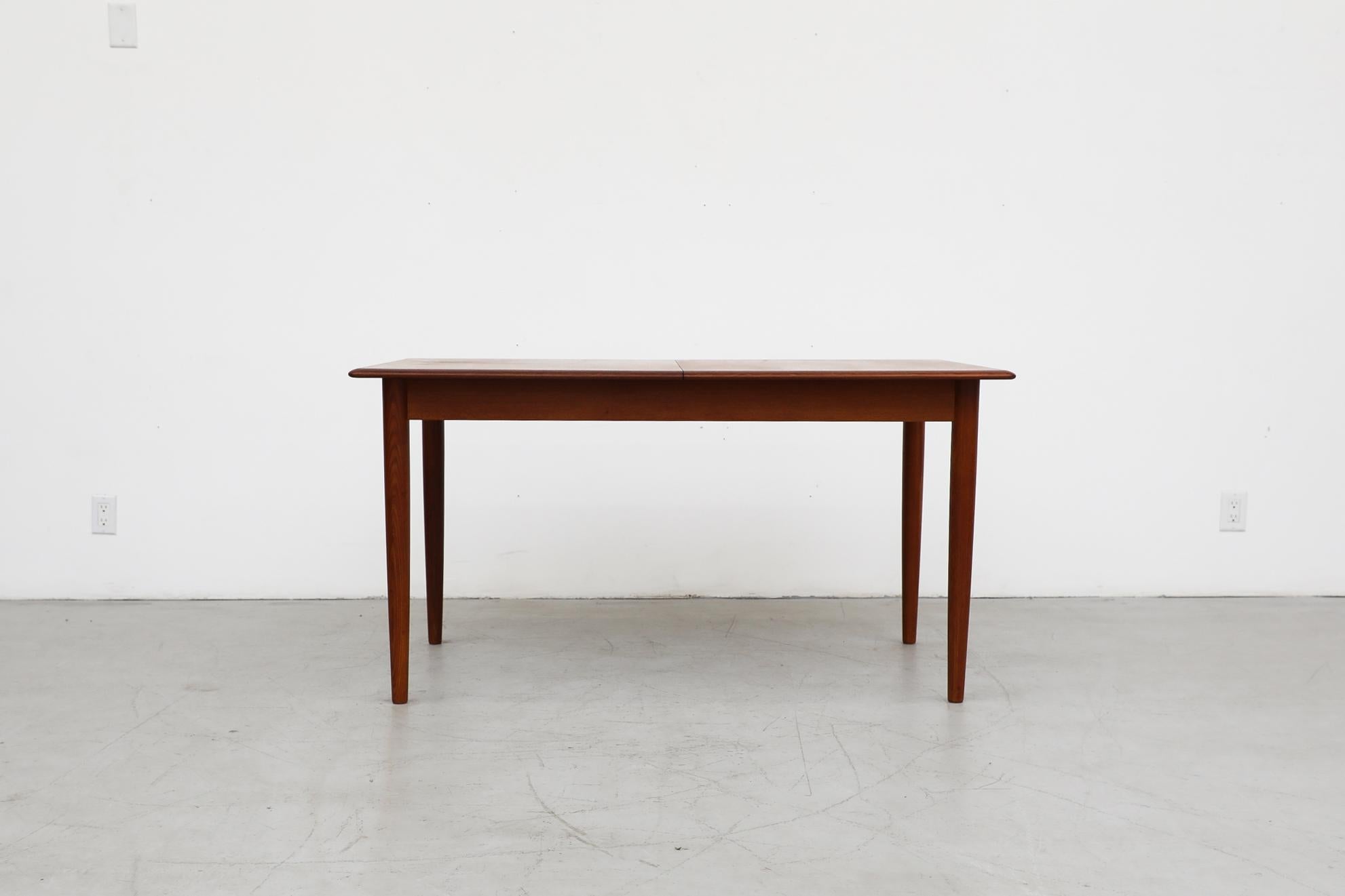 Beautiful lightly refinished, Danish midcentury teak dining table with masterfully carved edges and butterfly leaf. In original condition with light visible wear consistent with age and some use.