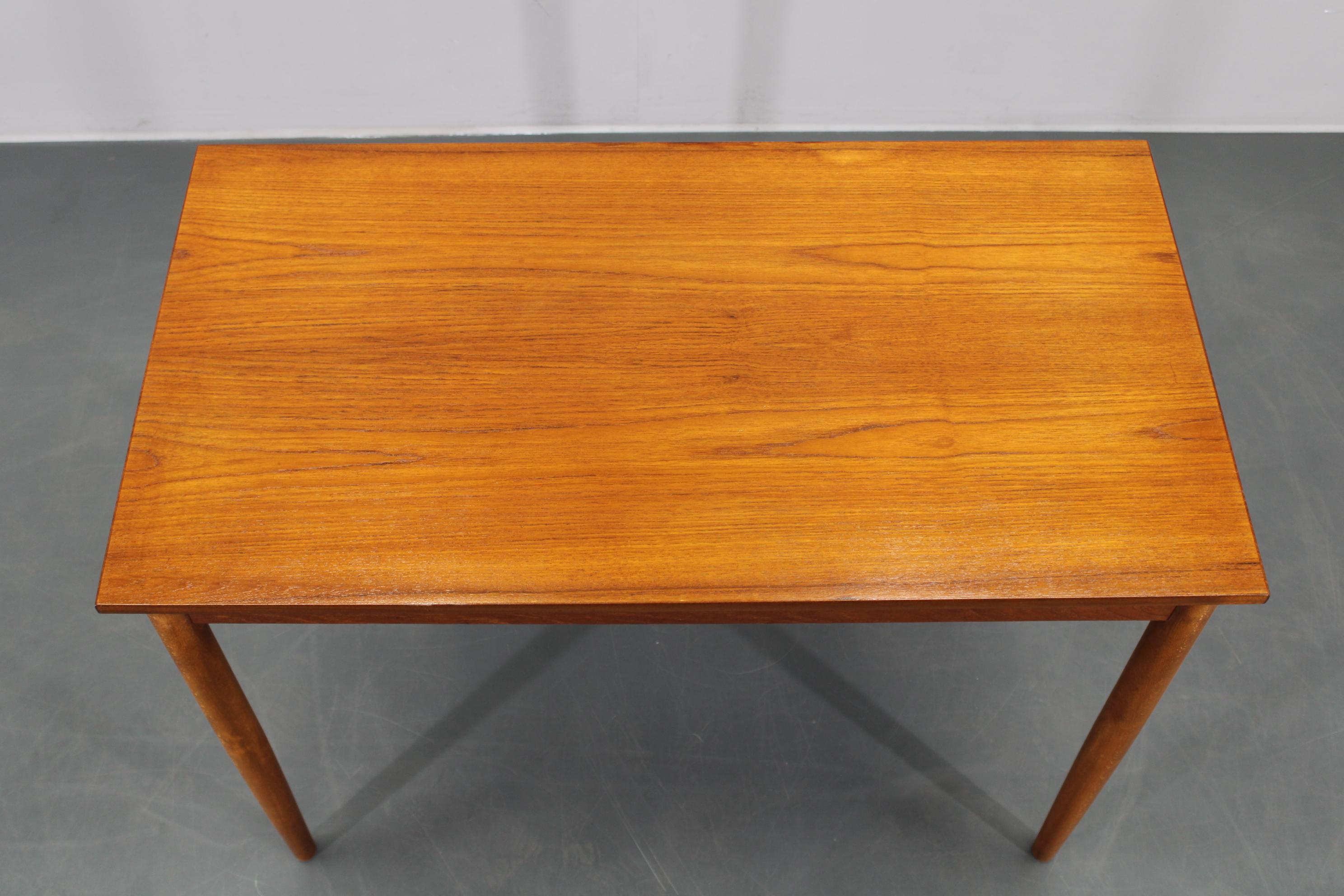 Tavolo da pranzo primario realizzato in Danimarca, intorno agli anni '60, con piano rettangolare in impiallacciatura di teak e gambe in faggio massiccio, esemplificativo del classico design scandinavo. Accuratamente ristrutturato e in ottime