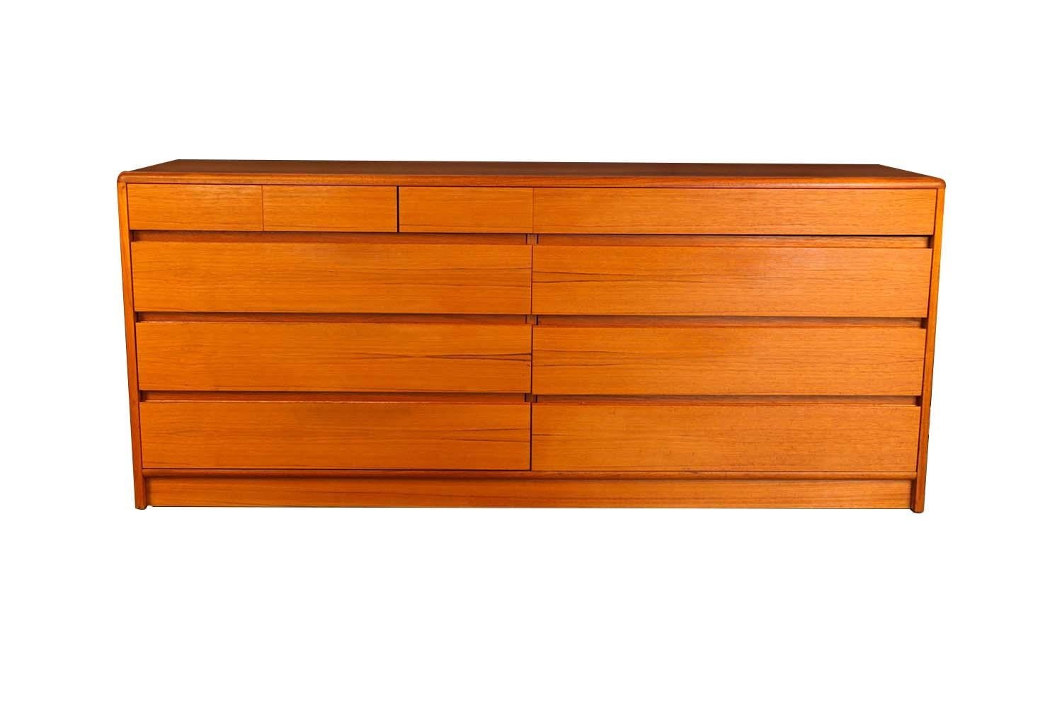 A minimalistic teak double dresser by Nordisk Andels-Eksport. This Danish Mid-Century Modern teak double dresser with ten drawers is Minimalist in style. This simply elegant dresser features an asymmetric drawer arrangement with three small lingerie