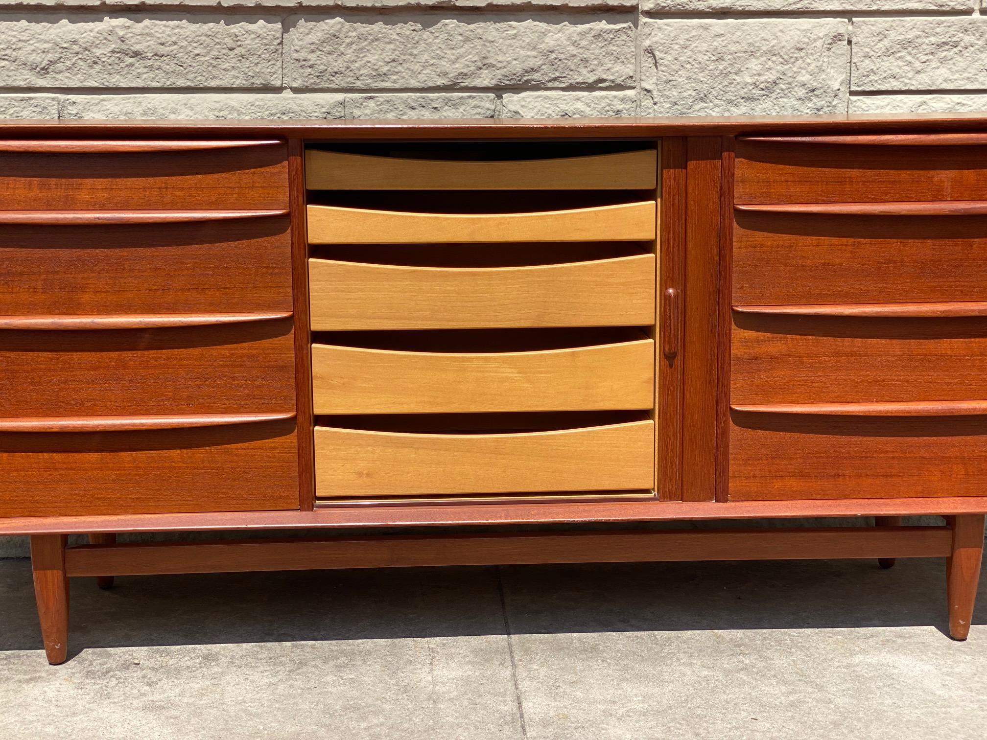 Danish long dresser in teak with tambour door features eight exposed drawers with center tambour section which opens to more interior drawers. This is perfect for garment storage or to be used as a credenza for any interior space. This long dresser