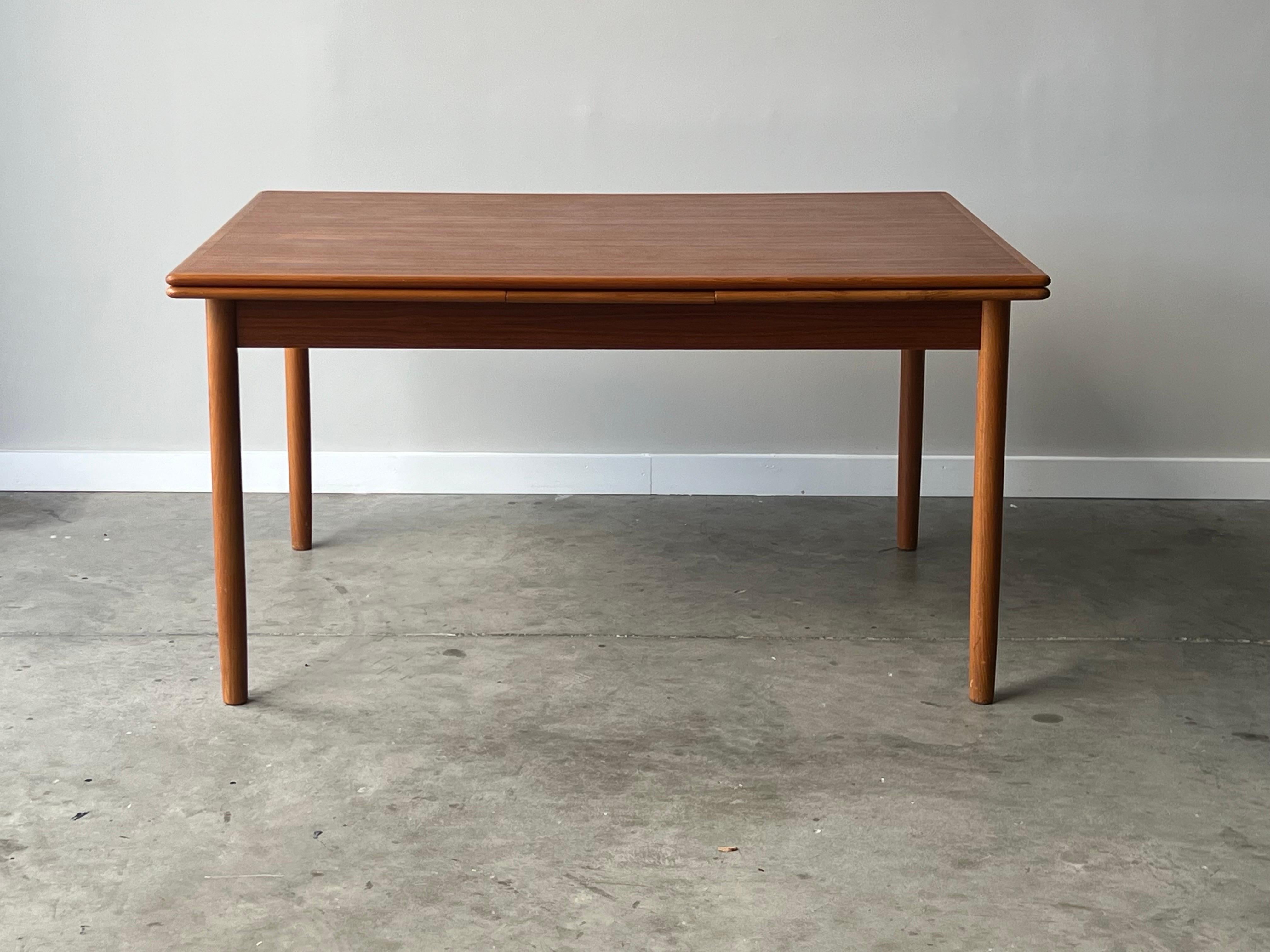 Beautiful expanding and hidden leaf danish teak dining table with gorgeous grain through out. This table expands almost double in size by releasing the leaves which slide underneath. Tapered teak legs present this table elegantly and is compatible