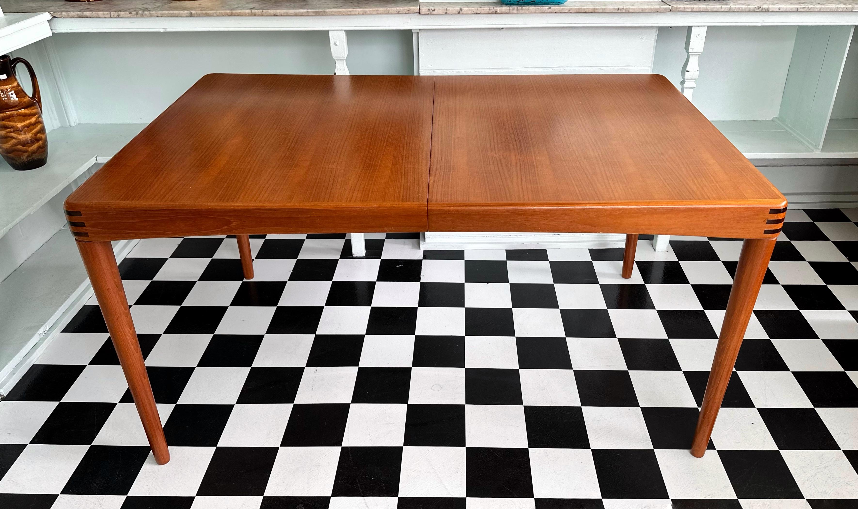Beautiful mid-century modern Danish teak rectangular extendable dining table. Having one separate extension (which is kept underneath the main leaf when not in use), this table is very versatile. It is comprised of very stylish tapered legs (which