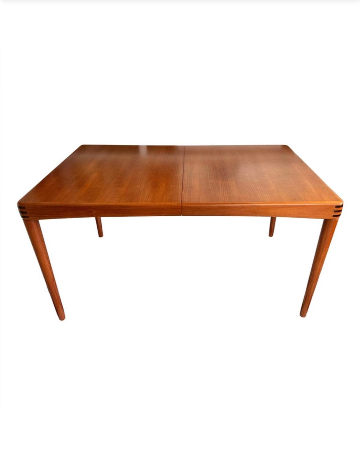 Beautiful mid-century modern Danish teak rectangular extendable dining table. Having one separate extension (which is kept underneath the main leaf when not in use), this table is very versatile. It is comprised of very stylish tapered legs (which