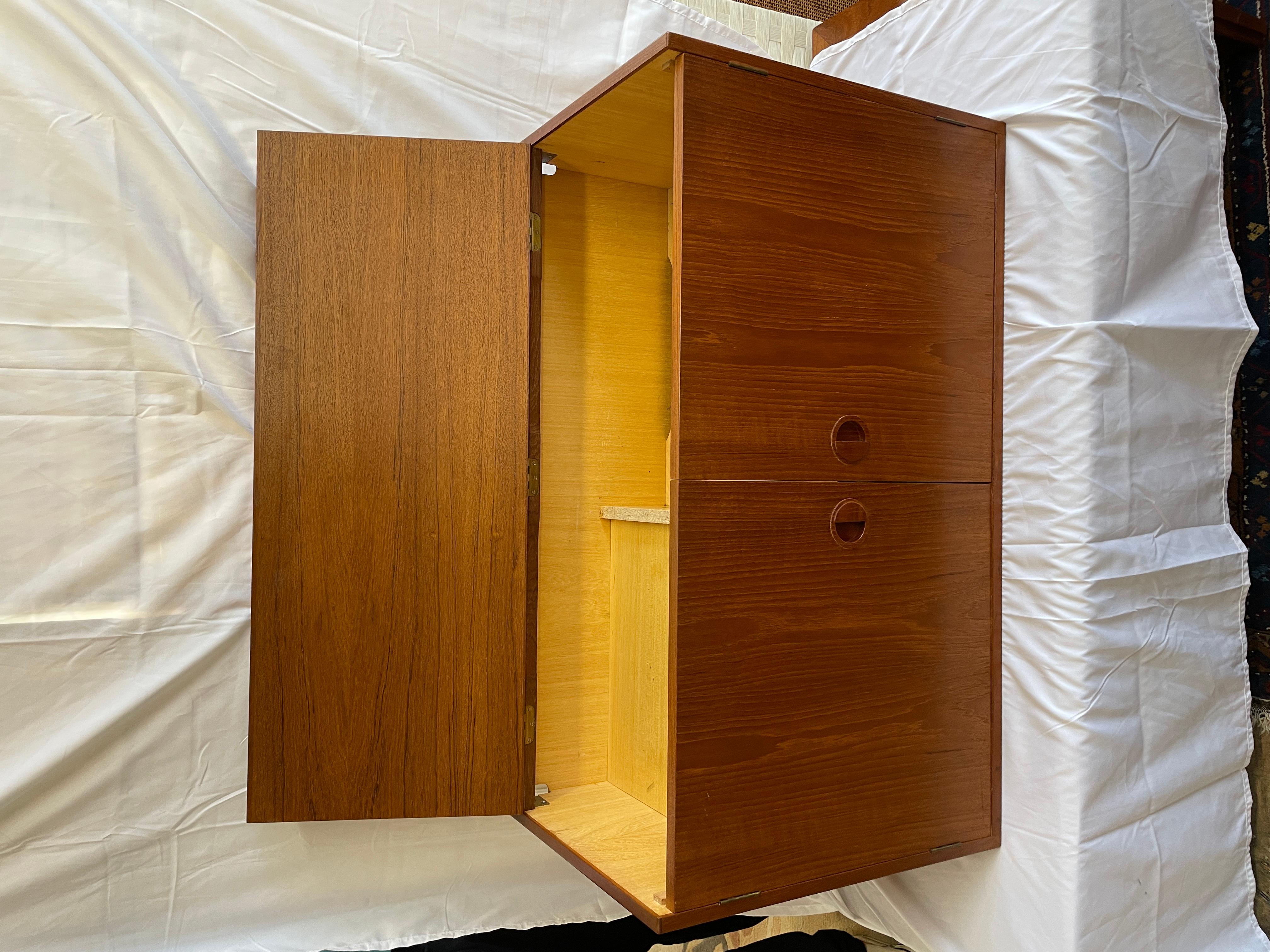 This is a handsome example of Hansen & Guldborg s craftsmanship. This particular unit has hinged top along with pair of door fronts, perfect as media unit. Inside there is is shelf on right with original cutout for cords. On left, is taller shelf